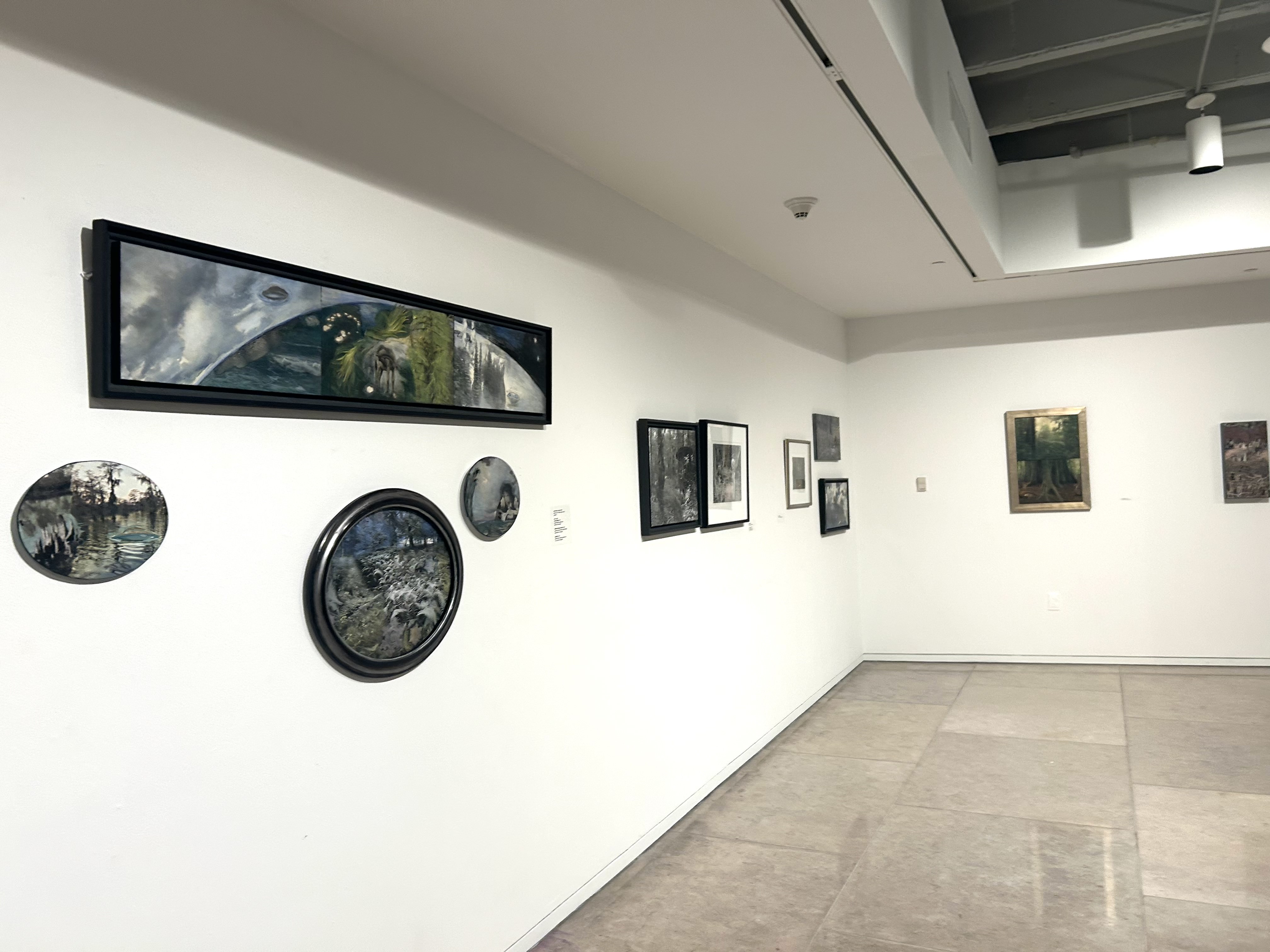 Several artworks hung on the wall of an art gallery by a curator