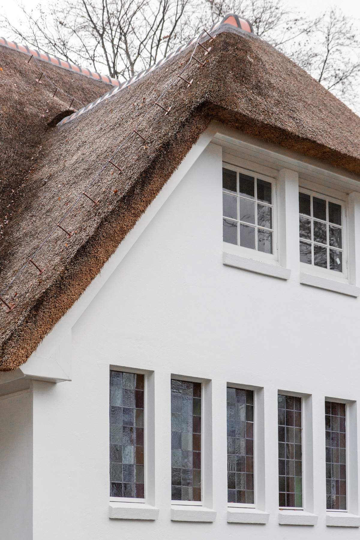 oude gevel klooster met rieten dak en glas in lood ramen