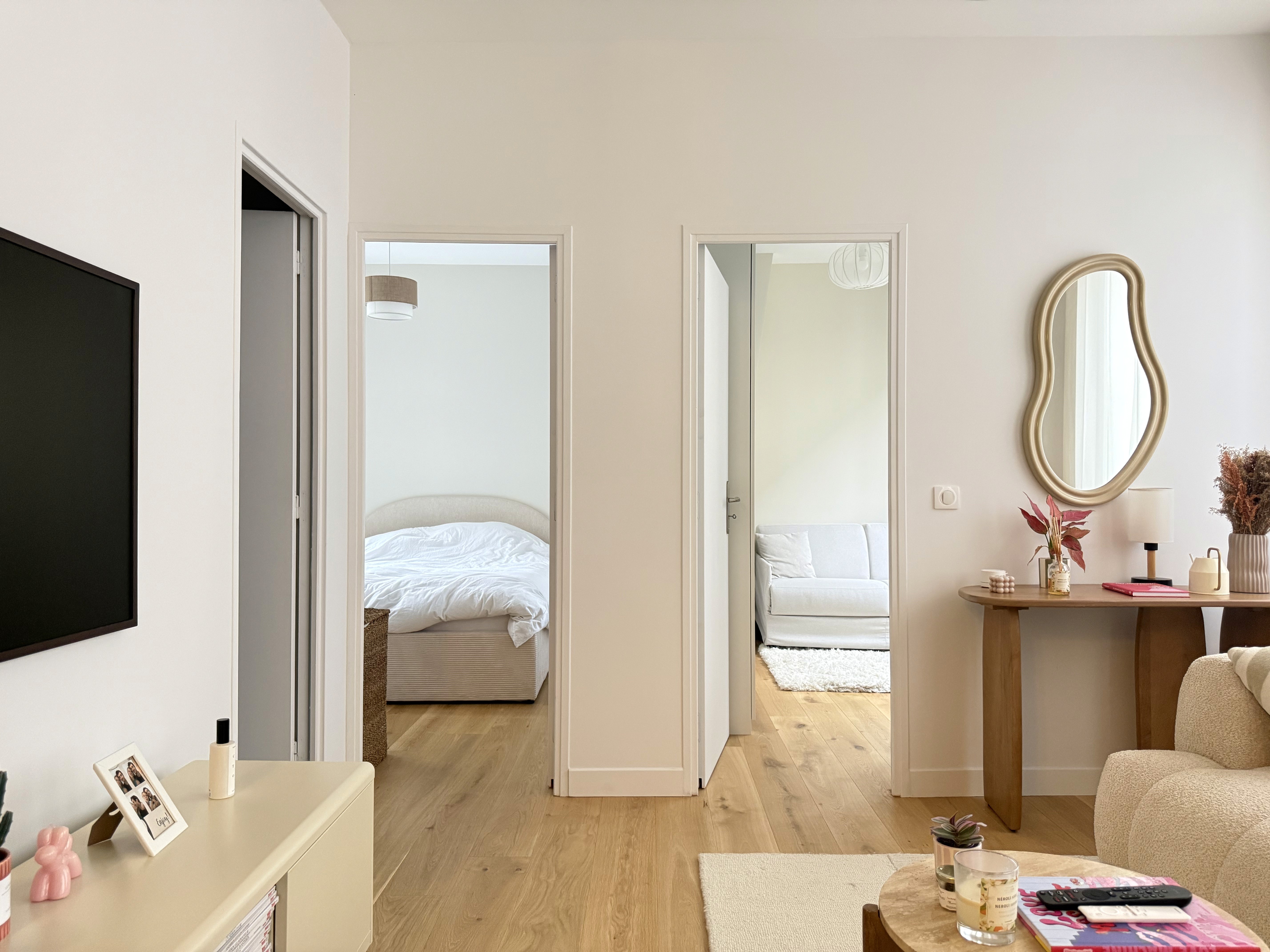 Vue depuis le salon vers les deux chambres, montrant une circulation fluide et une décoration minimaliste avec console en bois.