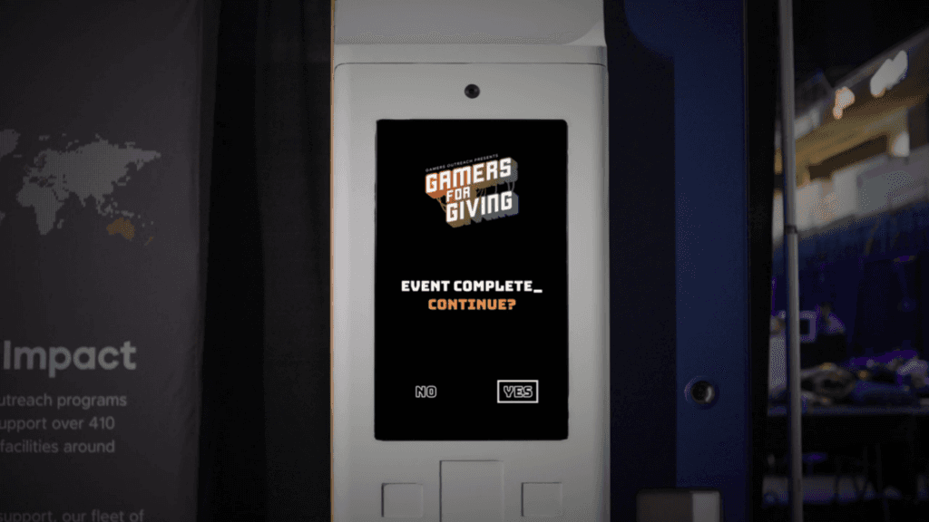 Photo of a Gamers Outreach Save Point Machine with a Gamers for Giving logo and the text "Event Complete_Continue? No Yes". The Yes text is highlighted with a white box outline.