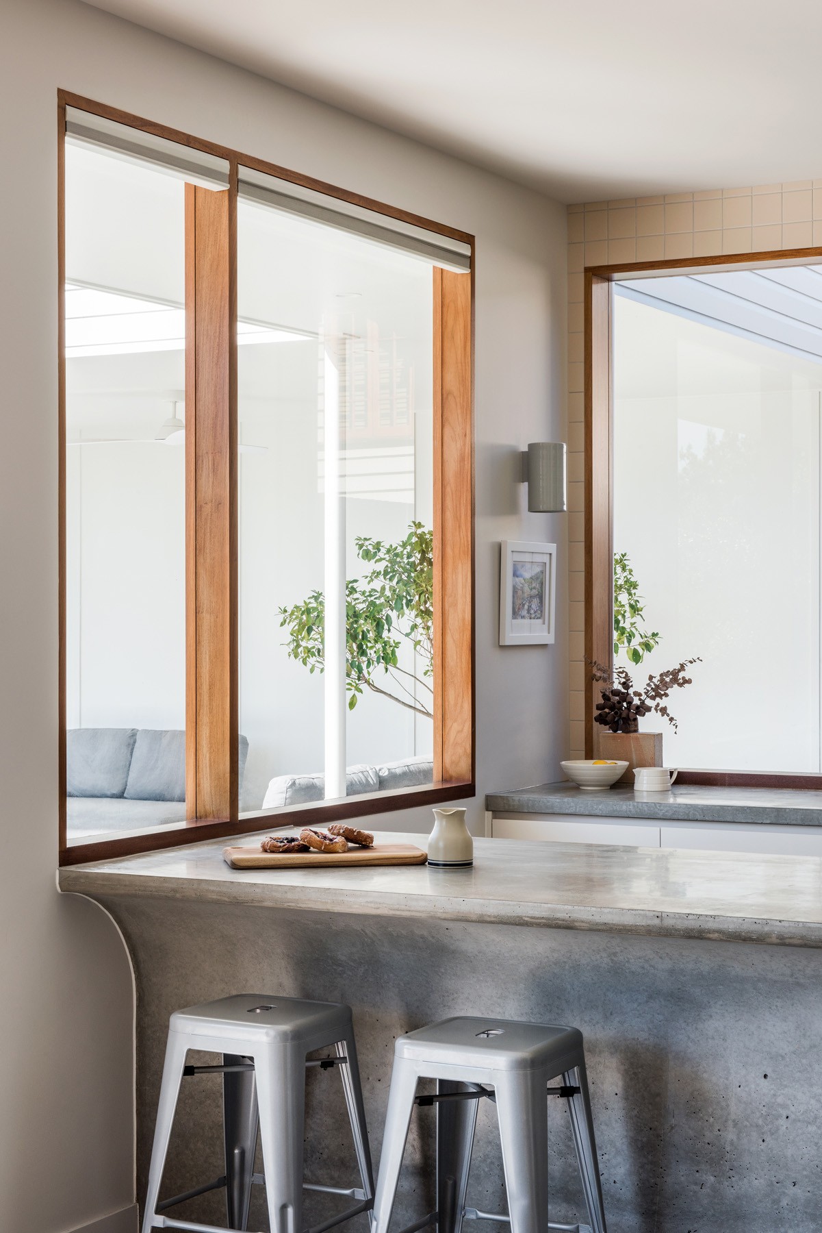 Kitchen detail within Ridge House, with concrete benchtops, timber-framed glazing, and soft daylight shaping the restrained material palette.
