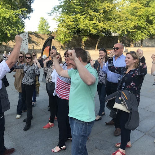 一群人在户外站着，举起拳头，微笑着做出庆祝的姿势，周围环绕着树木。