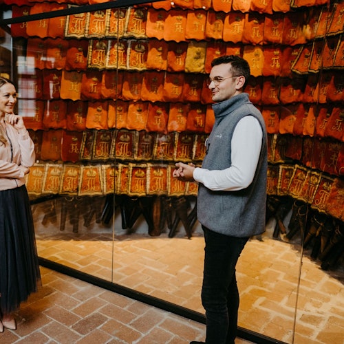 一位男子和一位女子站在一个展示柜前，柜中陈列着一排排红色和橙色的书籍封面，封面后是玻璃。