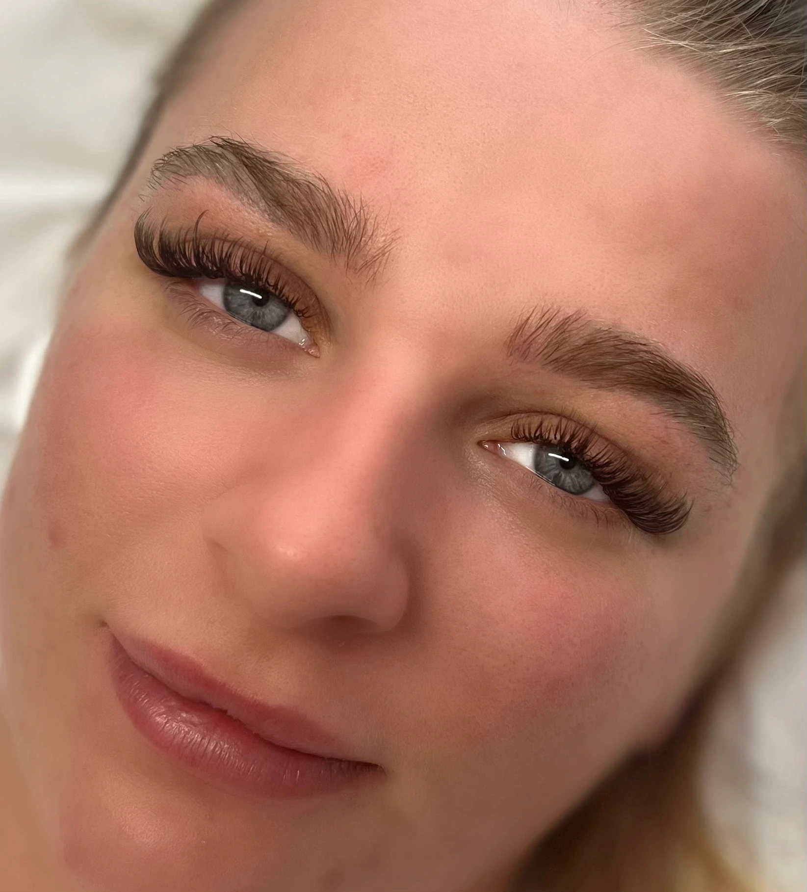 Client with blue eyes modelling the glam set eyelash extensions