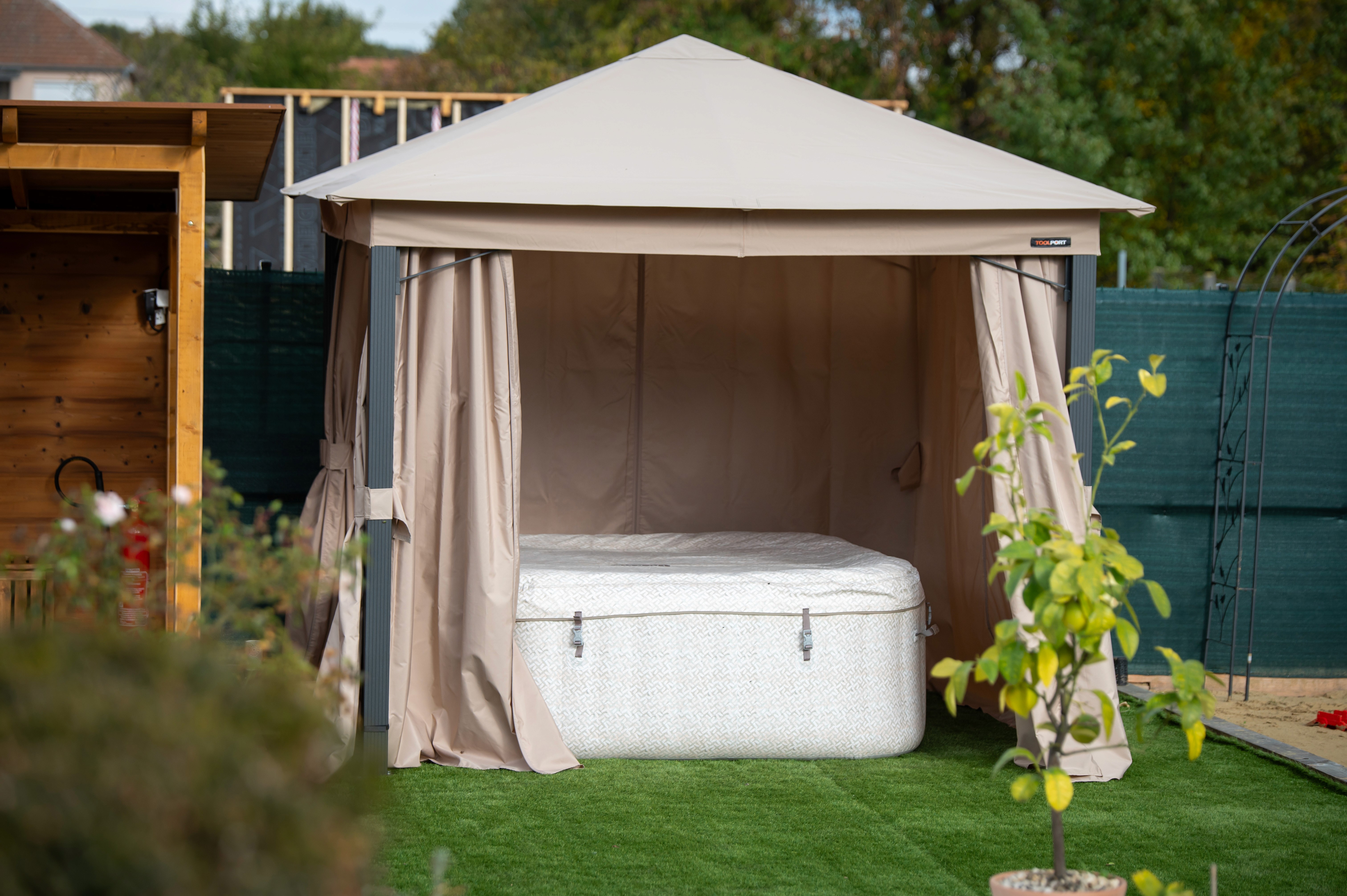 Bézs színű kerti pavilonban letakart jacuzzi.