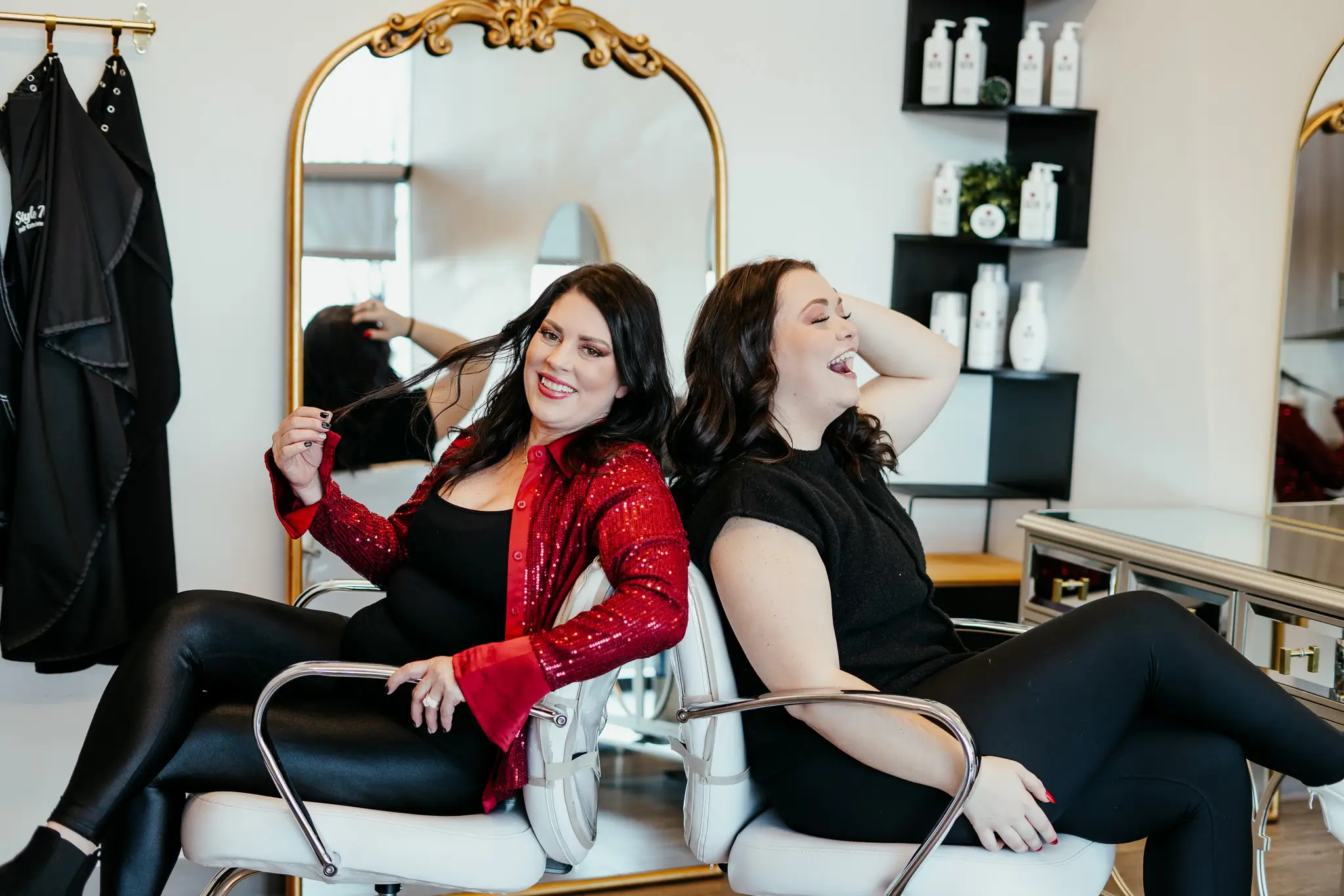 An image of Style Me Up team members facing back-to-back in their salon chairs.