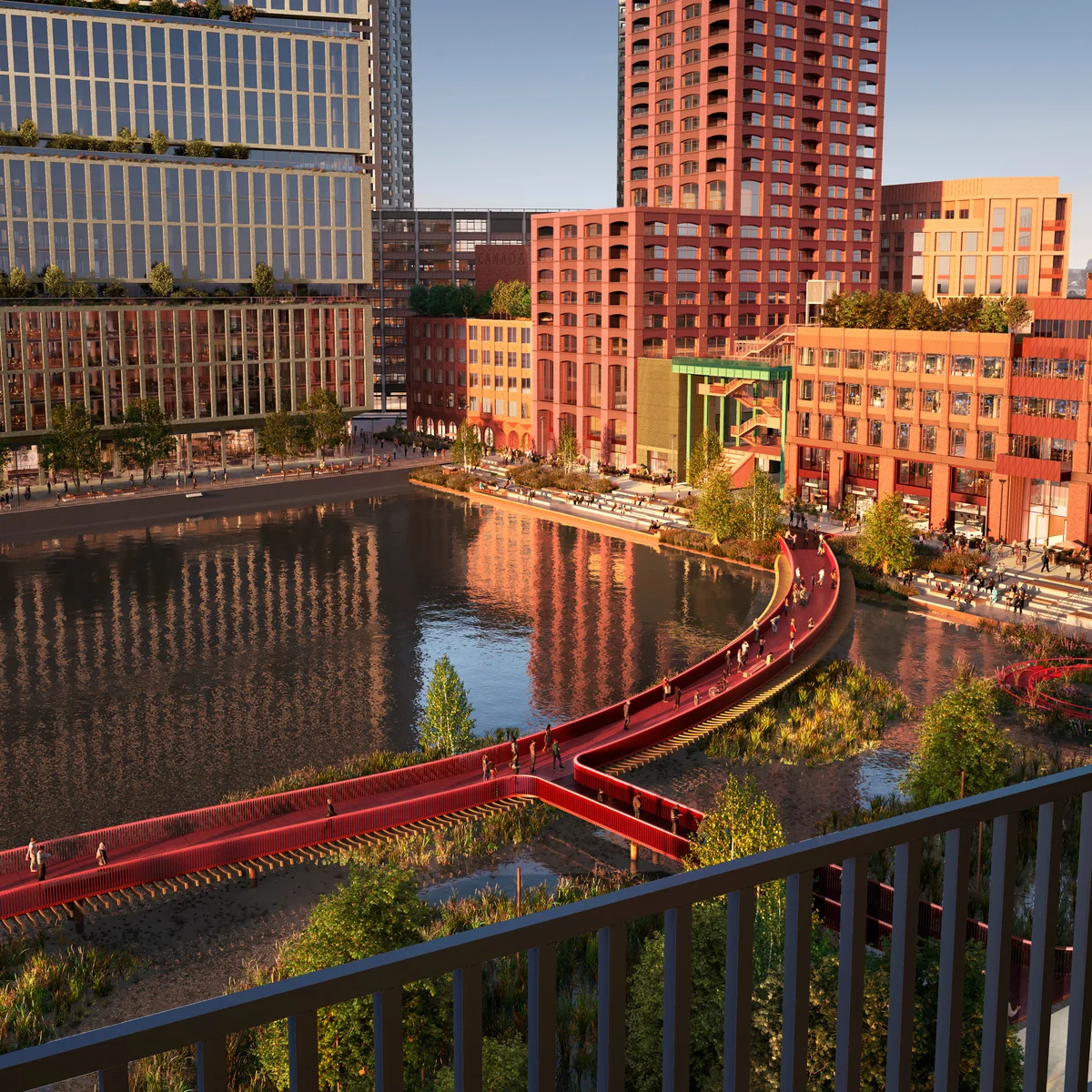 A smiling man with curly hair is sitting at a desk, looking at the camera, with a laptop and a lamp in the background.