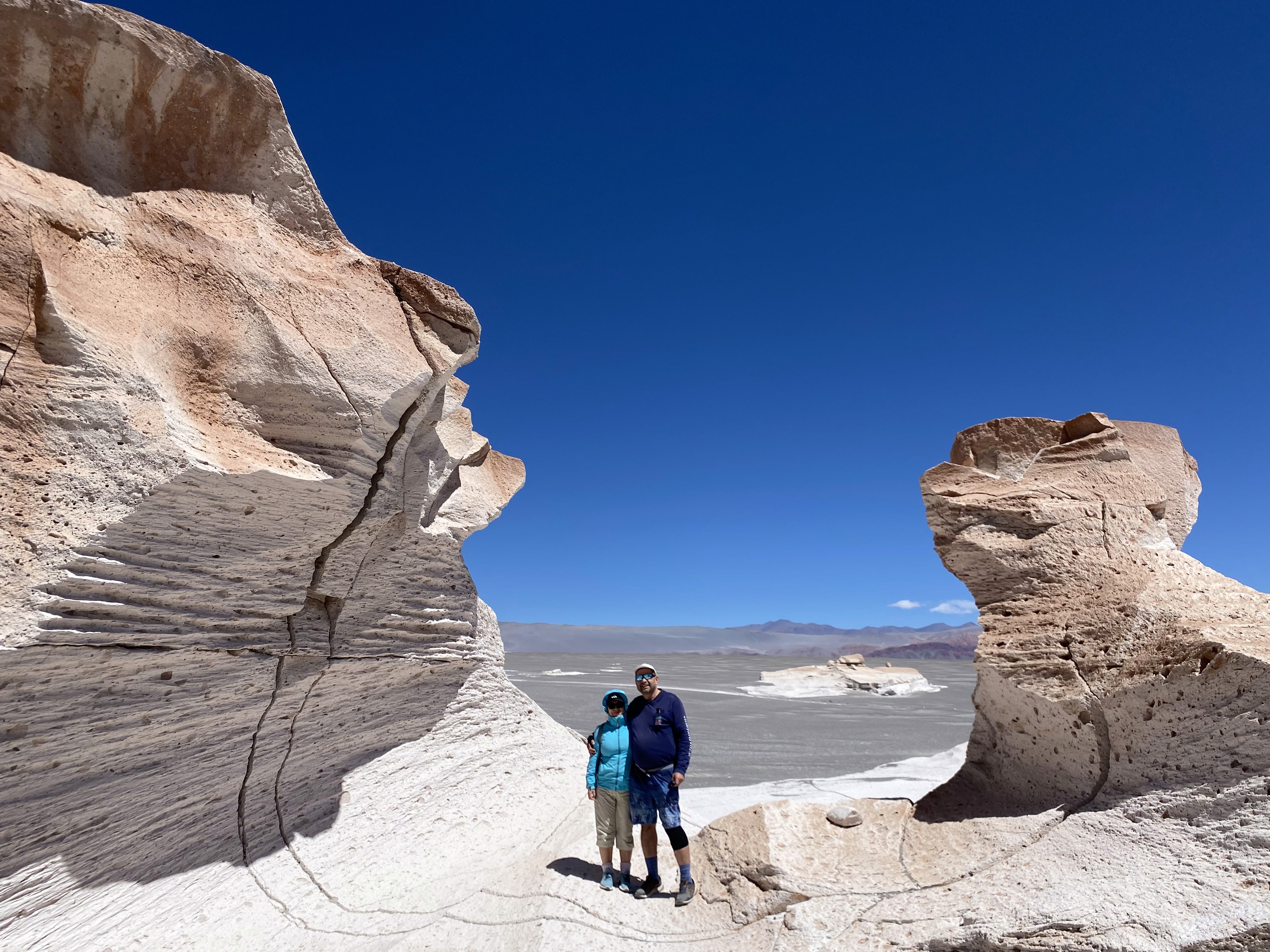 Mujer sentada sobre un tronco frente a una cascada doble en un bosque frondoso de Argentina.