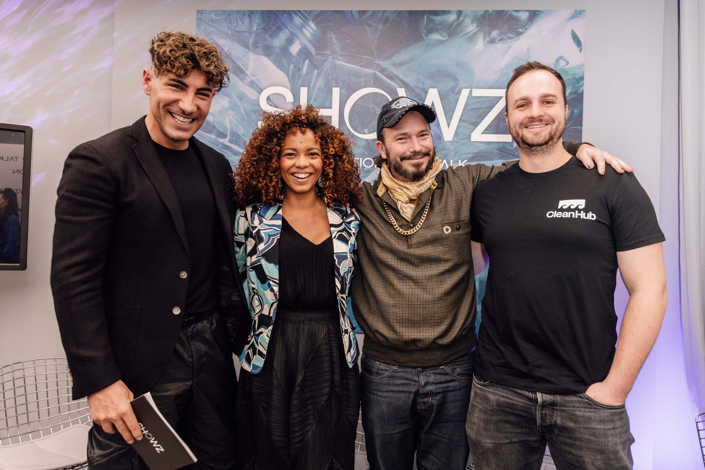Group photo of four smiling participants at the SHOWZ innovation talk event, including a woman in a patterned blazer and three men, one wearing a CleanHub T-shirt, standing in front of a branded backdrop
