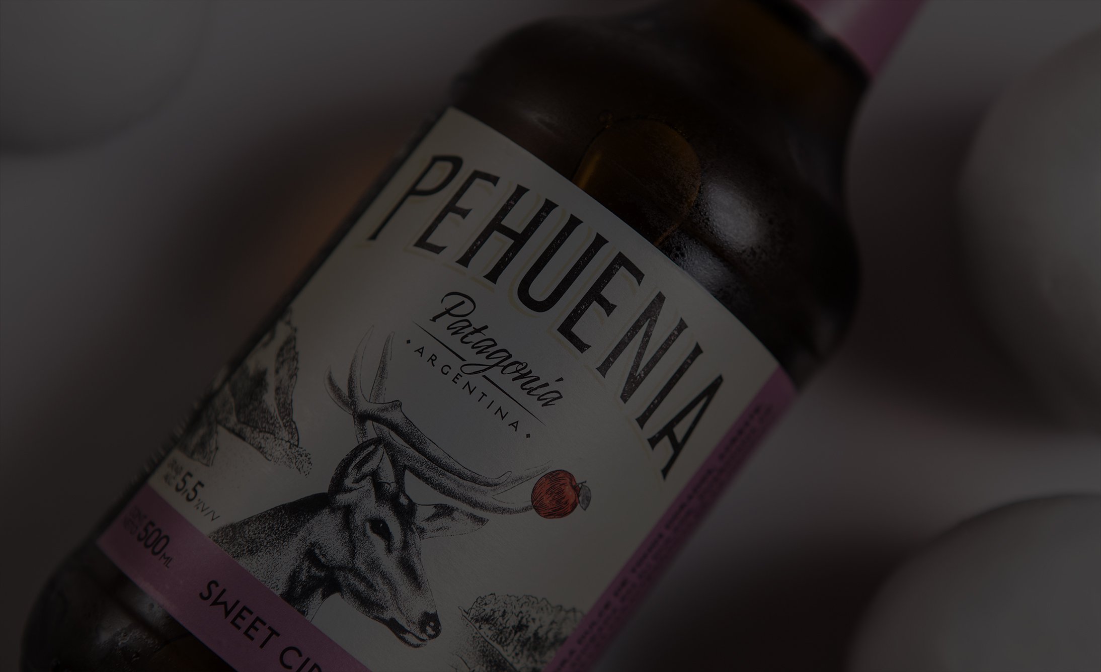 A bottle of Pehuenia, a Patagonian sweet cider, with a label featuring a deer and decorative elements.