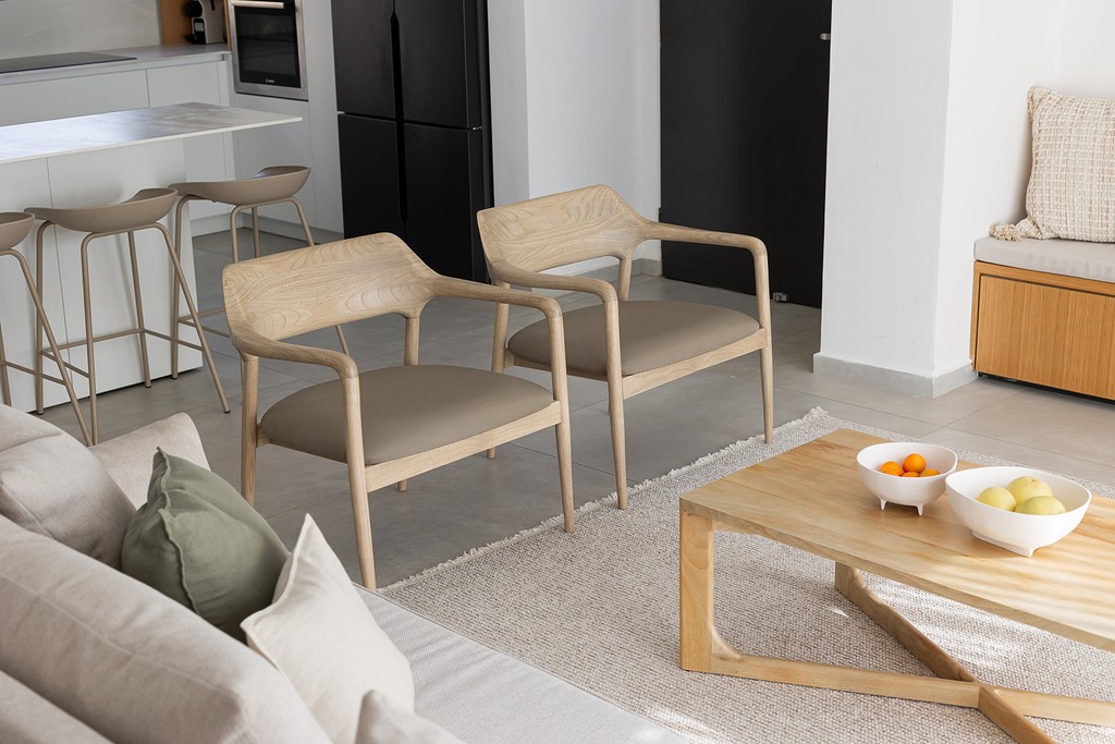 זוג כיסאות מודרניים מעץ בהיר עם מושבים בגוון בז'.