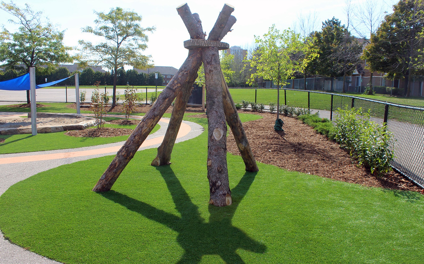 A wooden teepee nestled in a park, with AGL grass surrounding it, creating a playful atmosphere for kids.