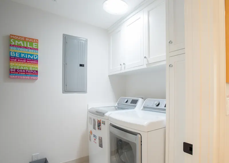 Laundry room with custom cabinetry and white appliances from the Big Canyon Remodel project. Photo by Chris Darnall.