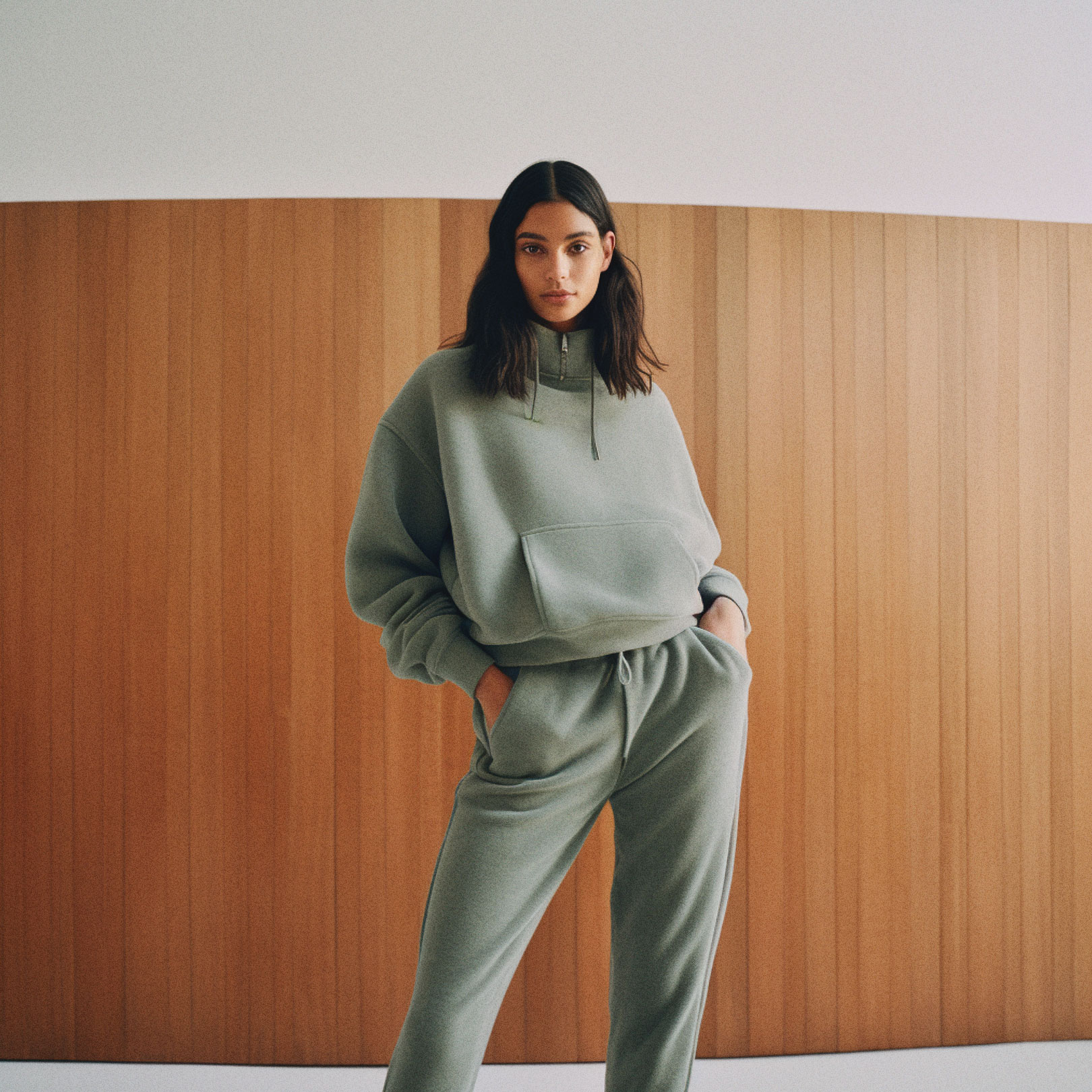 Woman in sweatsuit standing against wood wall