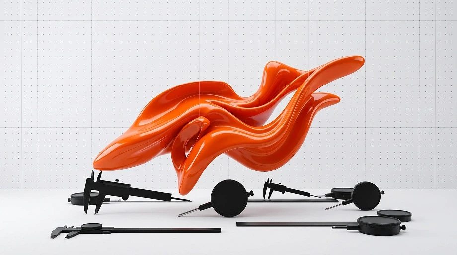 Glossy orange abstract form sweeps through the air above black rods, wheels, and mechanical parts on a pale gridded studio backdrop.