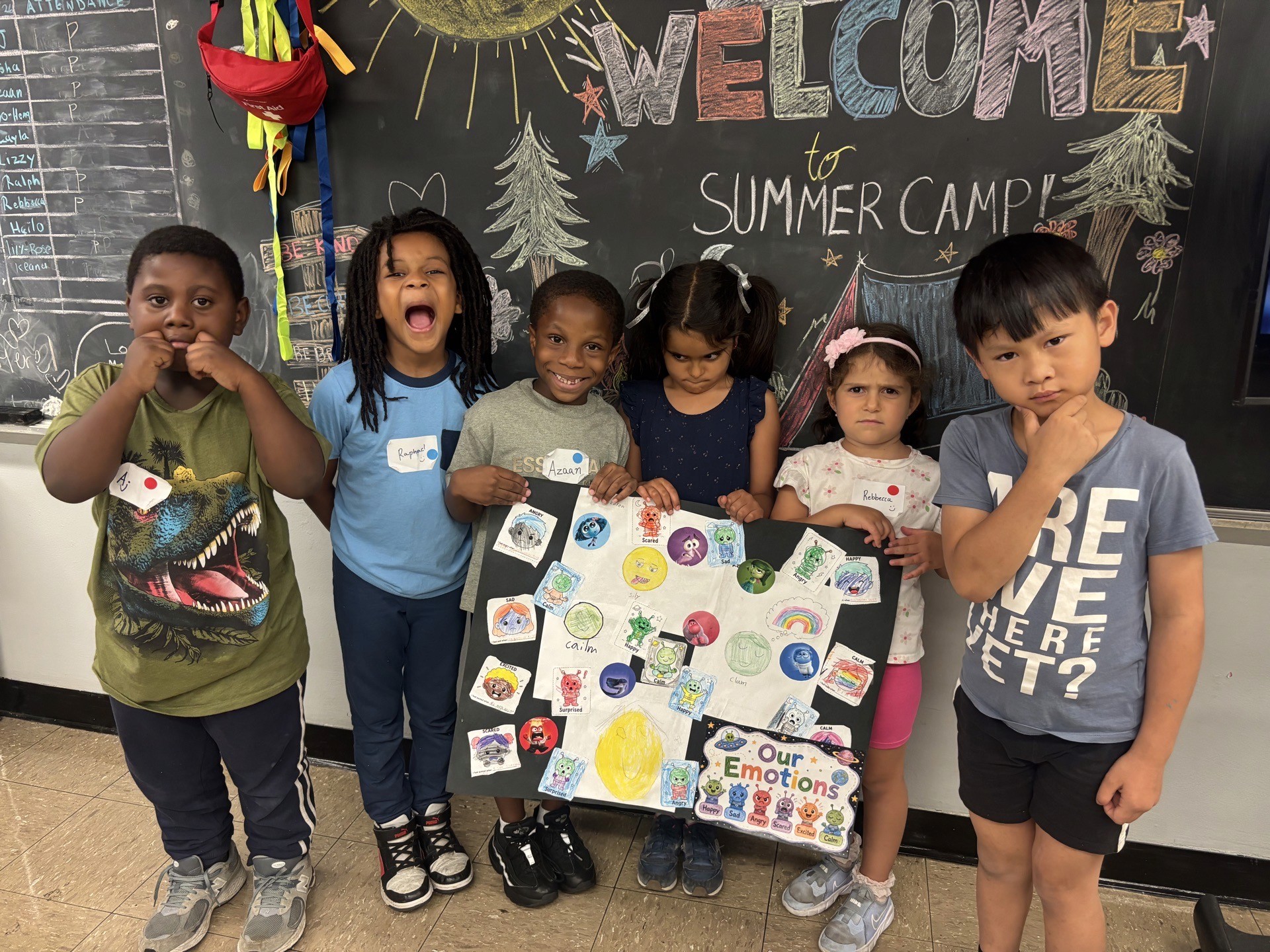 Participants make faces to express their favorite emotions and hold up a posterboard with a colorful representation of emotions and feelings.