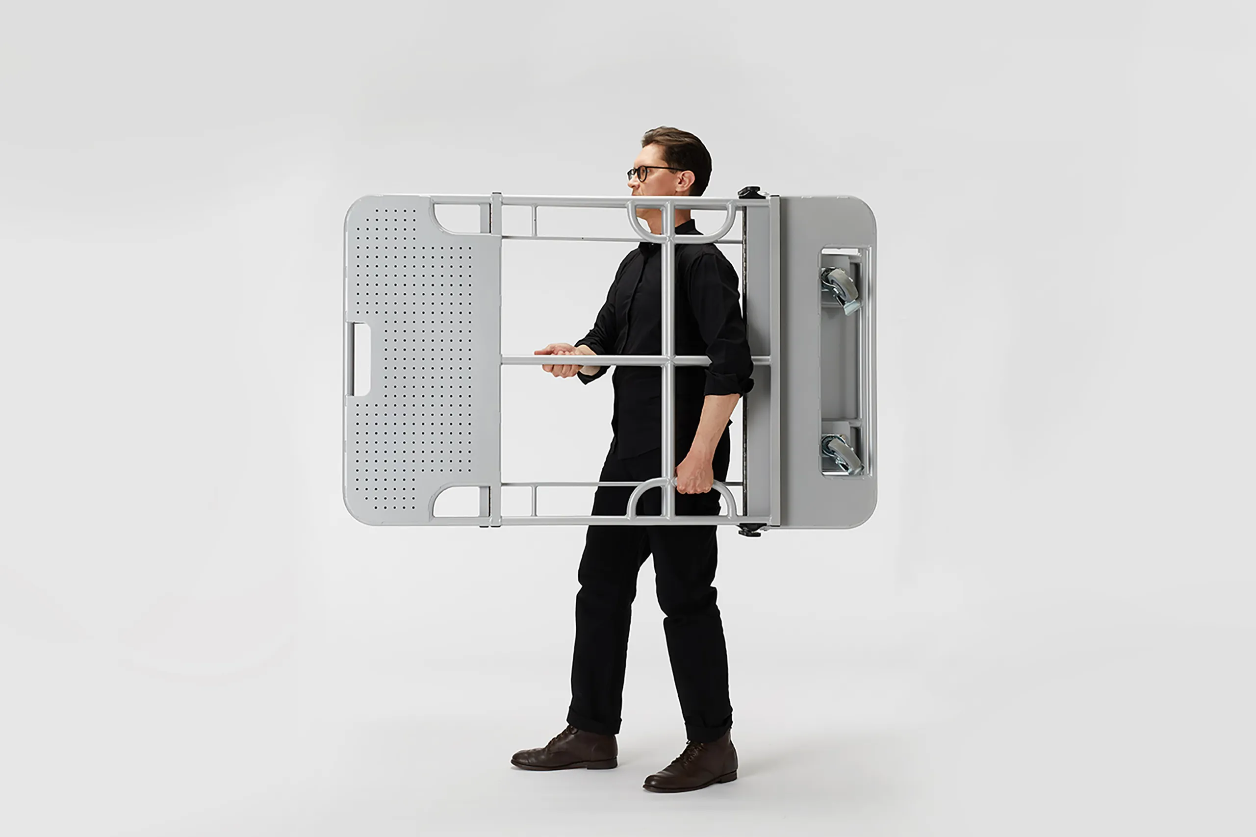 Person carrying the folded High Art Butterfly Cart by its integrated handle