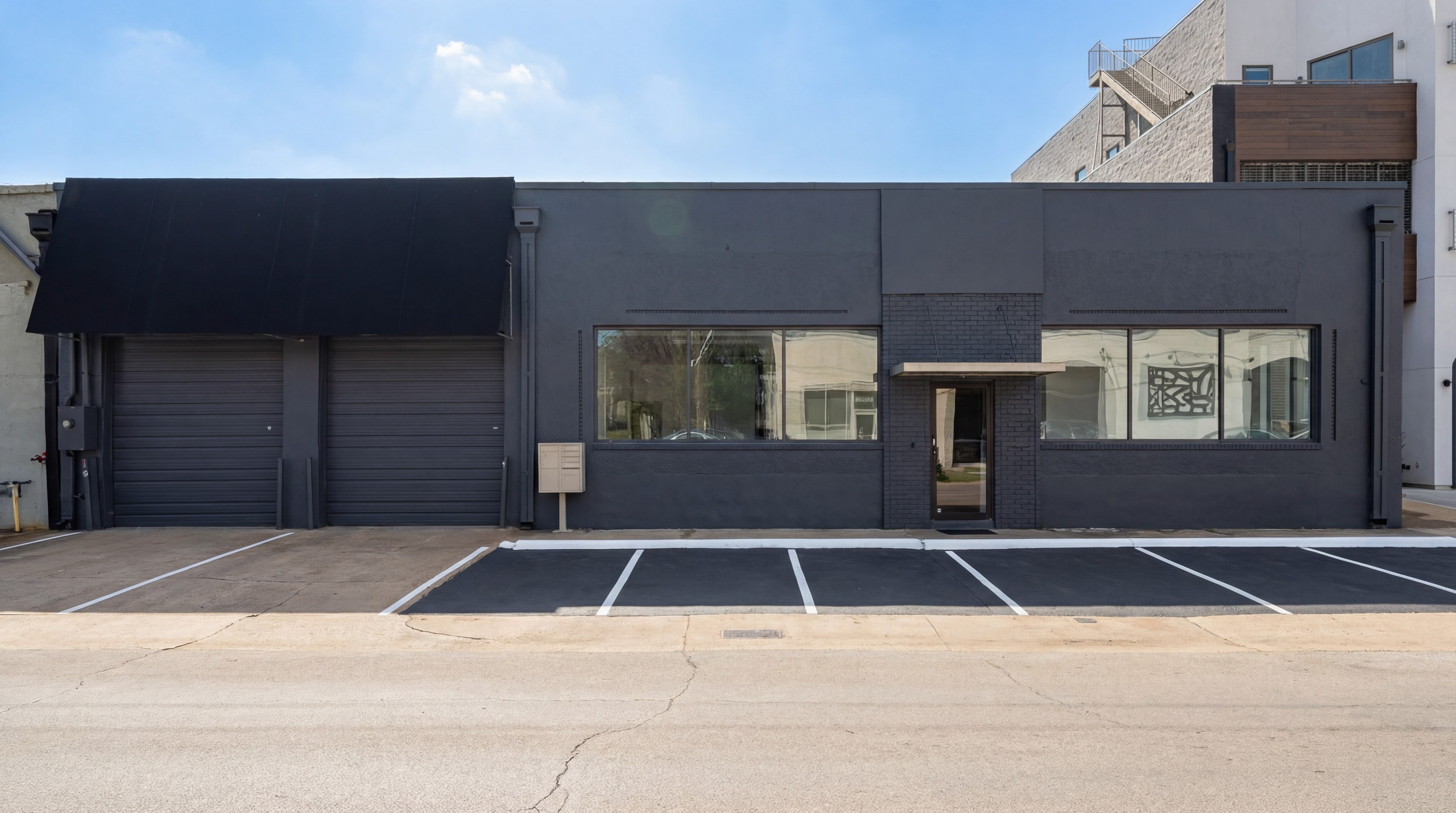 Modern red brick apartment or office building viewed from below against a blue sky, showcasing its geometric architecture with evenly spaced windows and balconies.