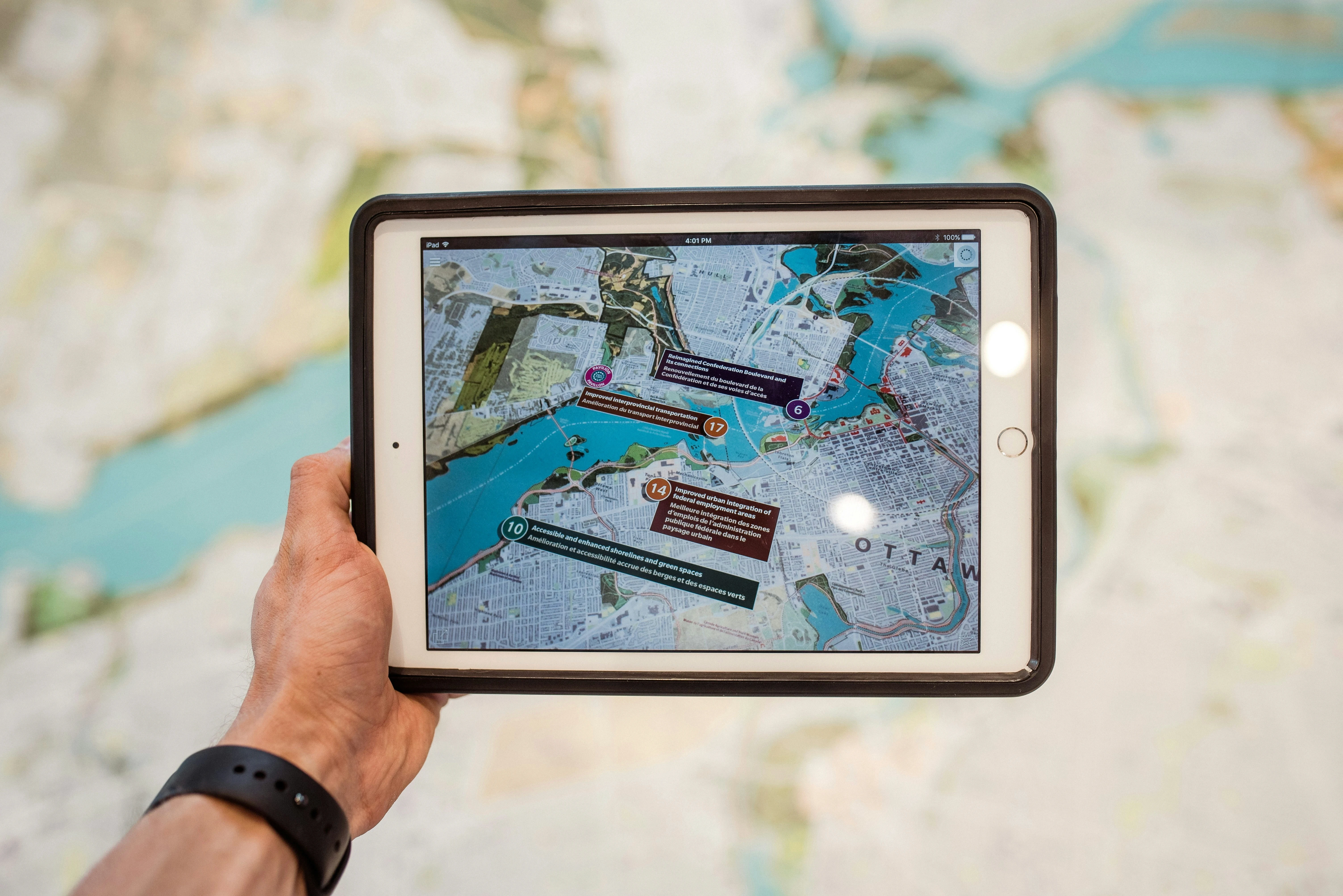 This image shows a hand holding a tablet displaying a digital map with overlaid markers, symbolizing the integration of Augmented Reality app development in mapping and navigation solutions. The digital interface on the tablet demonstrates how AR app development can enhance real-world data by layering interactive, location-based information over physical maps. The image represents the potential of Augmented Reality app developers in transforming traditional navigation systems into immersive, user-friendly AR experiences. By utilizing AR software, developers can create interactive applications that allow users to visualize complex geographical data with ease. This visual also emphasizes the importance of Augmented Reality software development in providing users with real-time, context-sensitive information, enhancing decision-making and navigation. The seamless blending of the digital map with the physical background highlights the power of AR app development to bridge the gap between virtual elements and real-world environments, a core aspect of modern Augmented Reality technology.