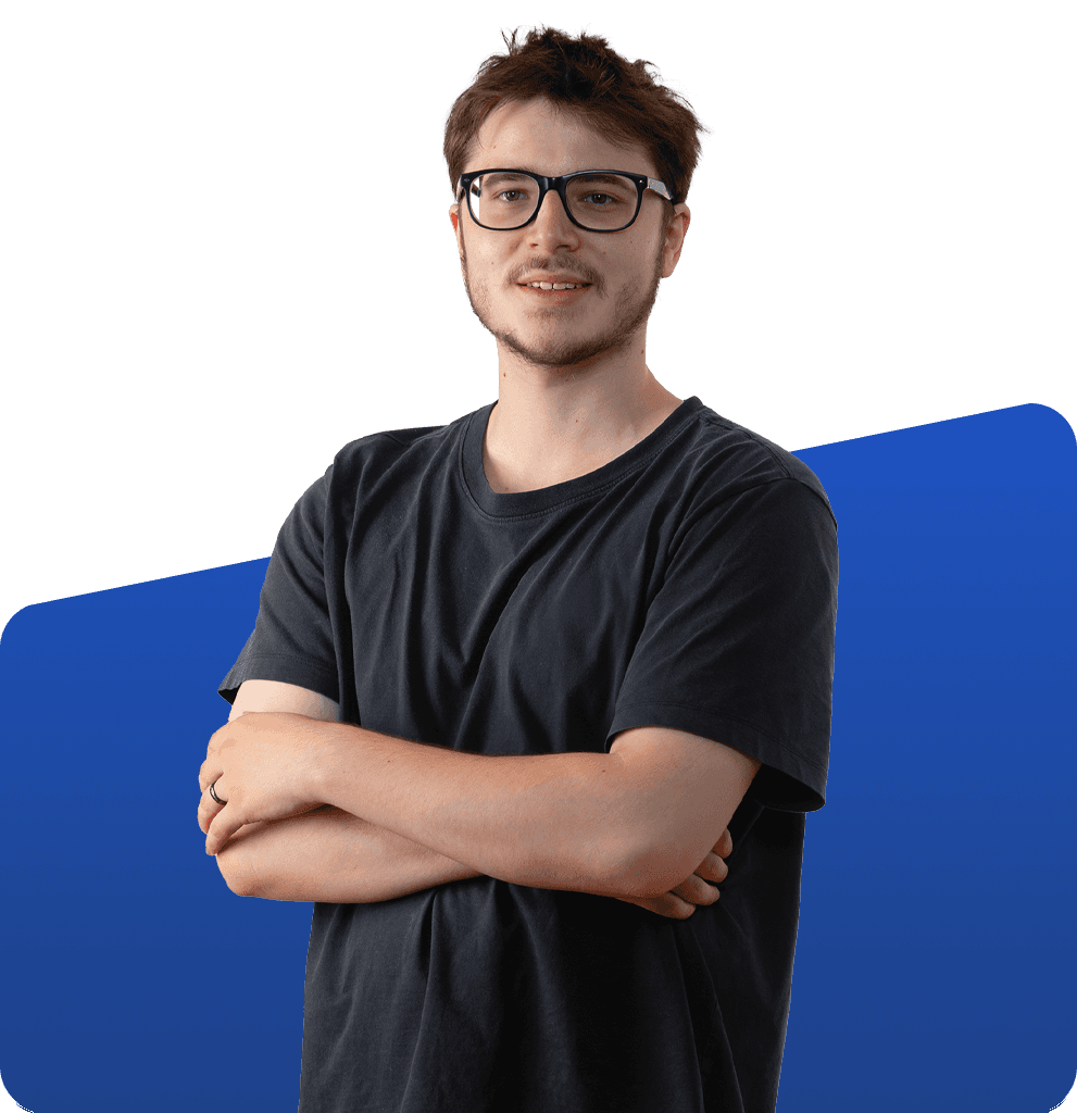 Portrait füm Geschäftsführer mit Brille und dunklem T-Shirt vor blau-weißem Hintergrund, Arme verschränkt