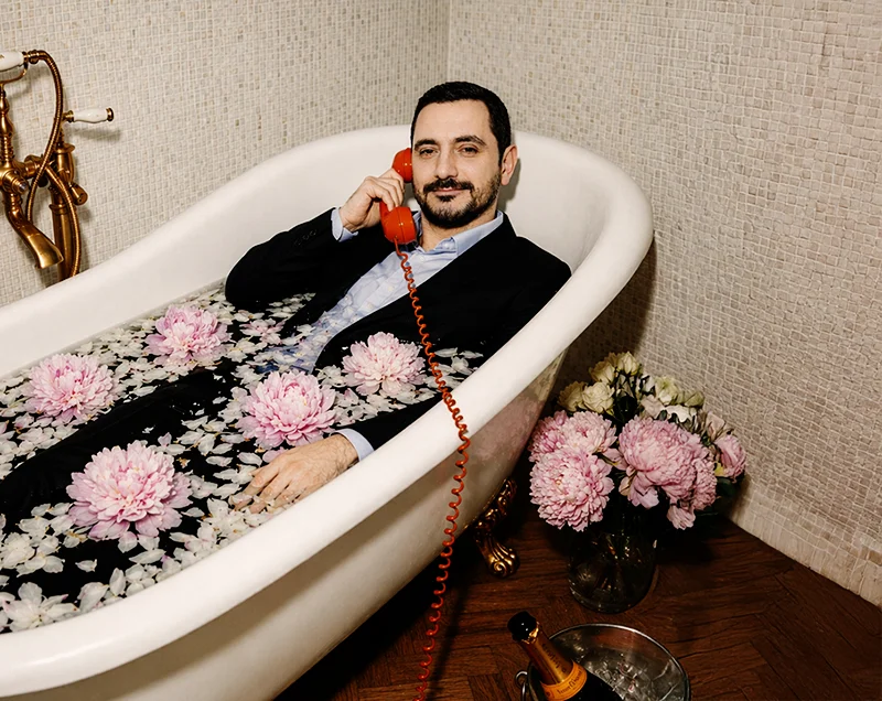 A close-up of a person wearing green-tinted glasses, with a serious expression and smooth skin.