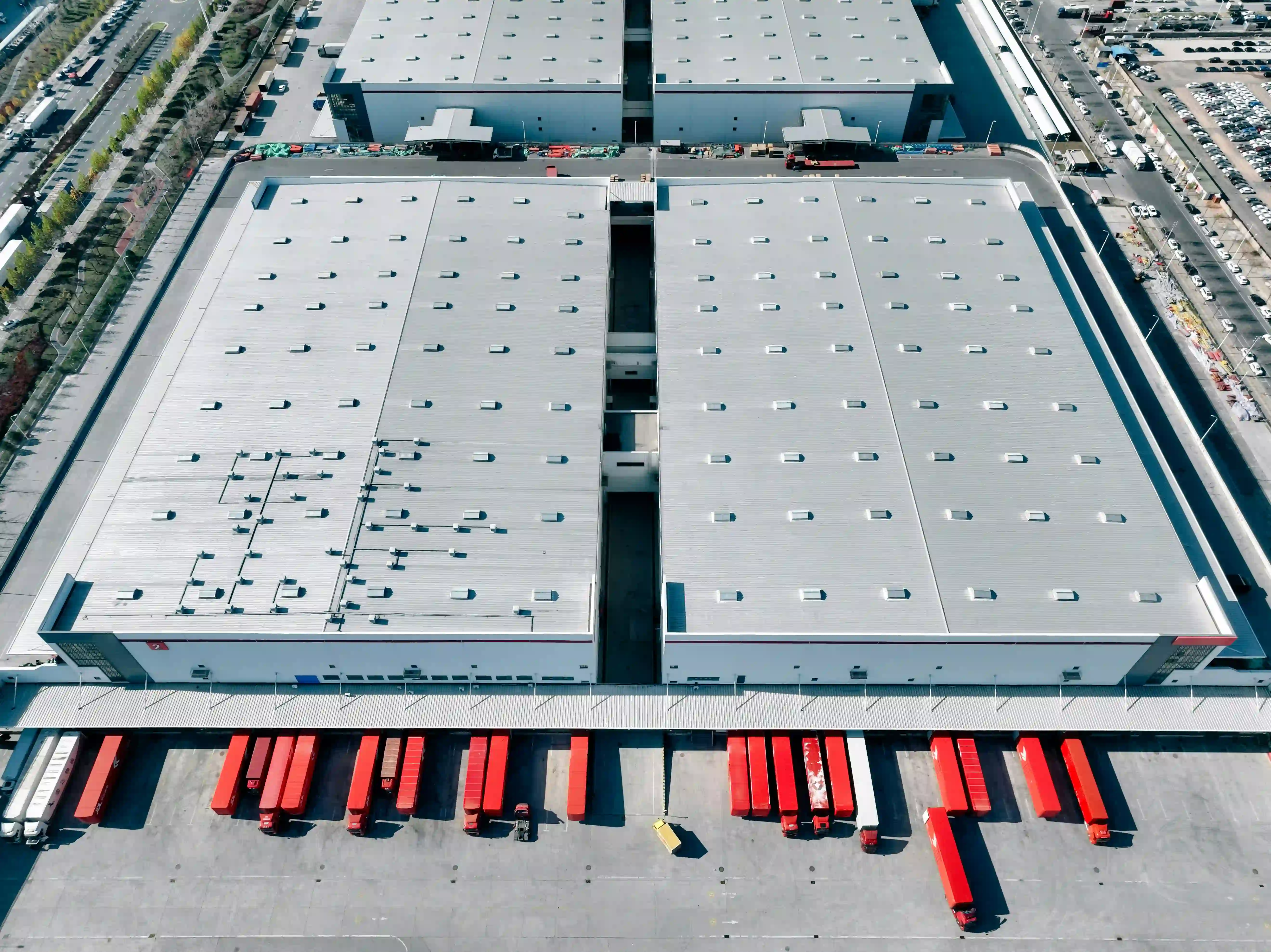 aerial shot of a busy 3PL warehouse with red lorry trailers in the foreground