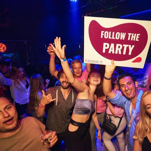 A group of pub crawl participants posing for a group selfie with a "Follow the Party - pubcrawl.pl" sign