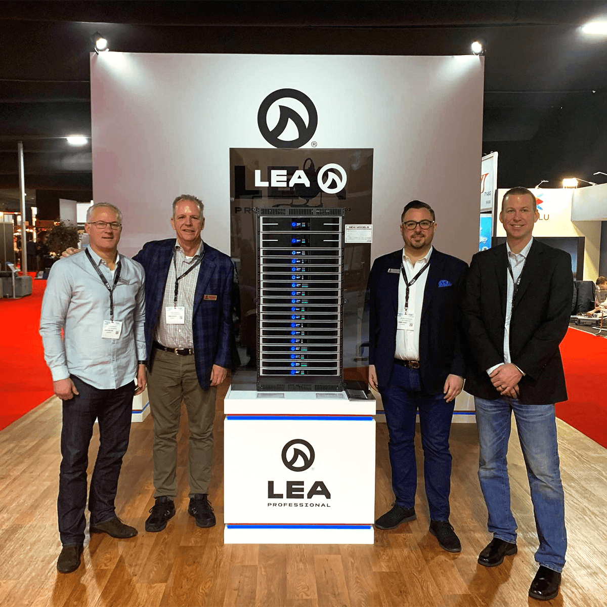 Four men stand behind a LEA Professional server rack