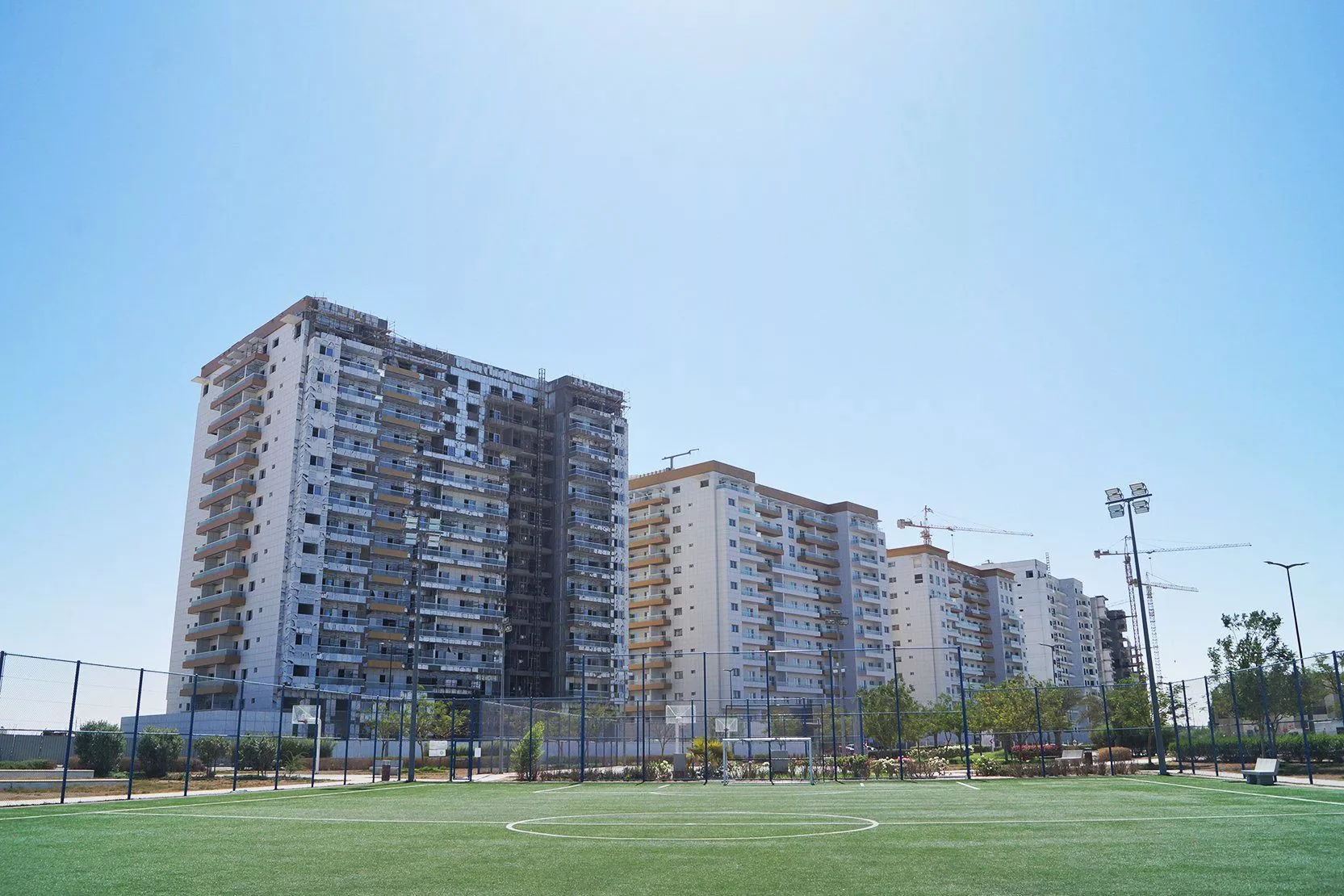 Modern residential buildings near a football pitch in Living Legends. Expert Dubai real estate services.