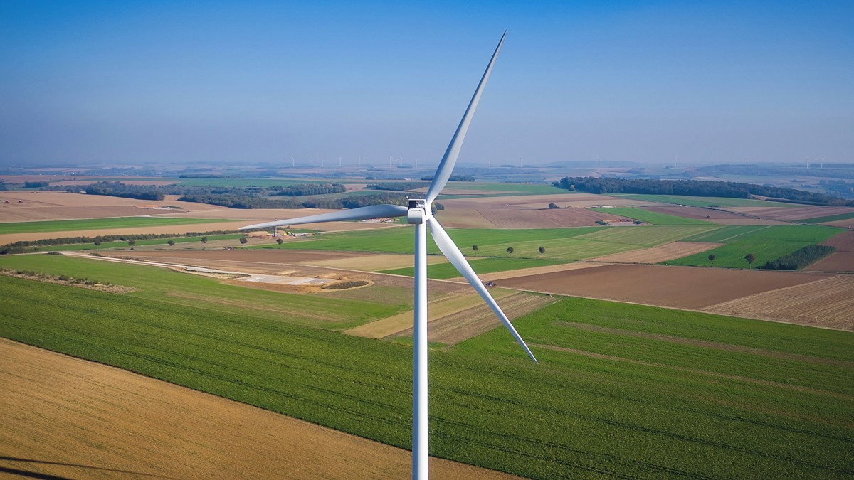 vue au drone d'une éolienne surplombant un paysage agricole