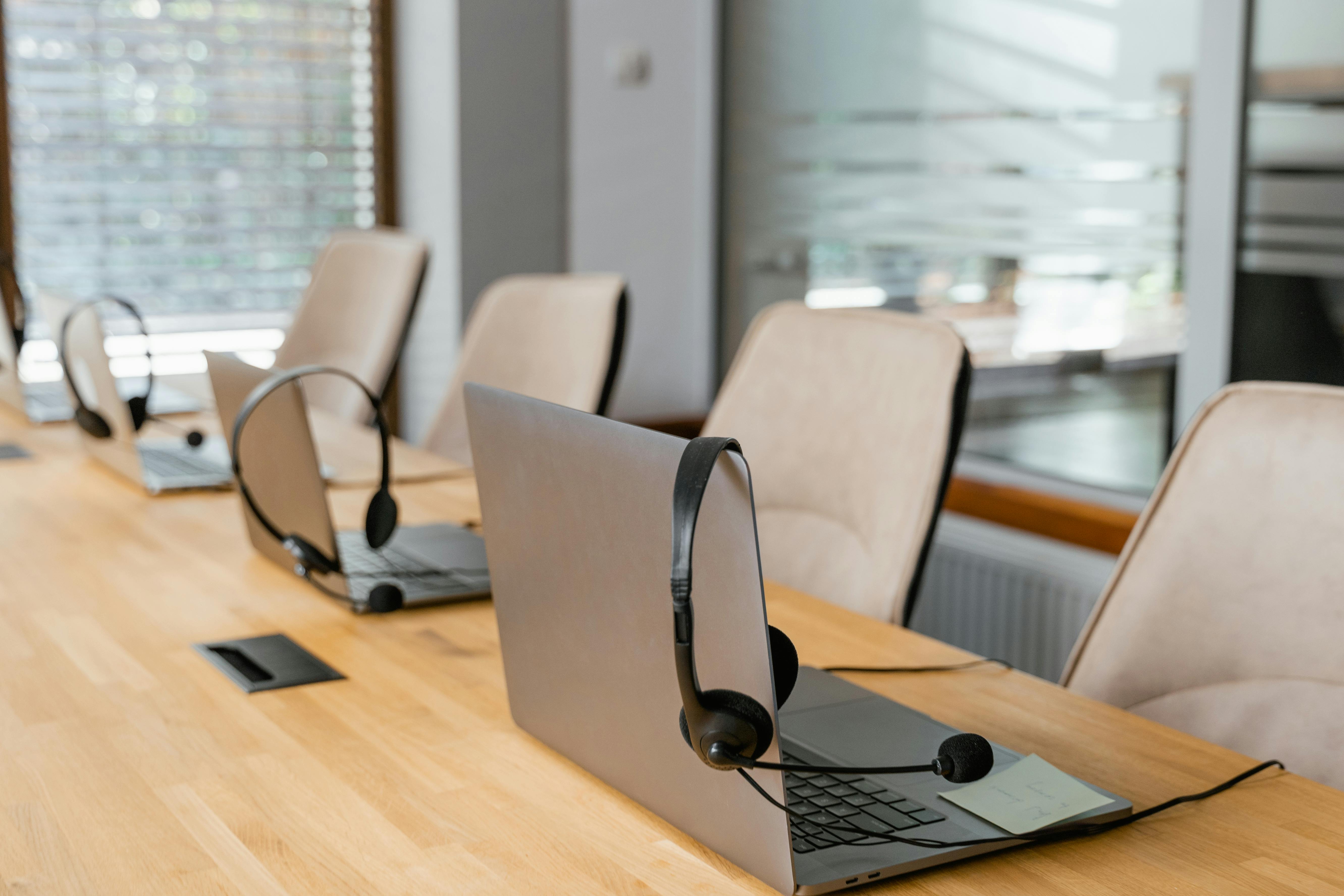 Laptops with headsets arranged on a conference table