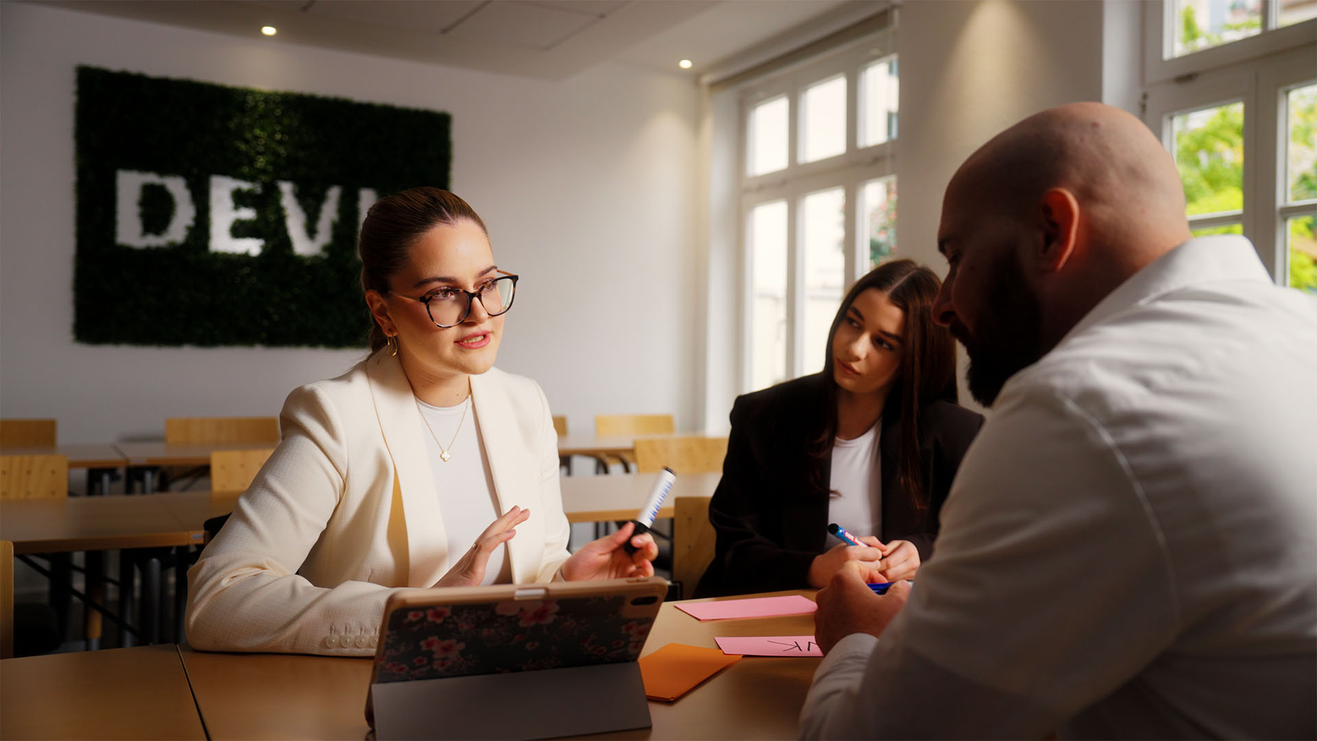 Three people discuss strategic film production for a social media campaign; a bright setting enhances the collaborative atmosphere.