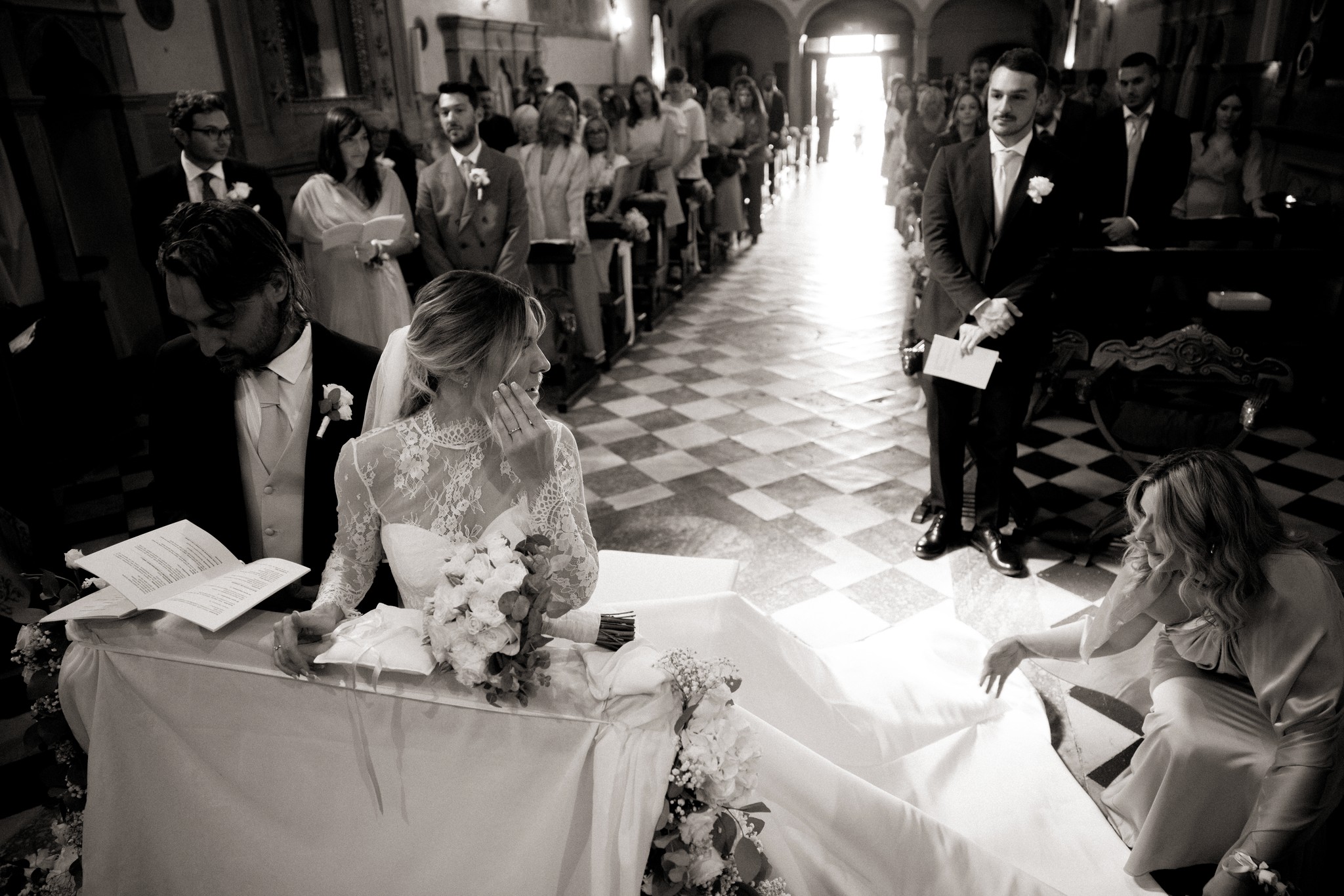 Sposi all'altare in chiesa a Bolgheri, cerimonia di matrimonio in bianco e nero, luce naturale che illumina la navata