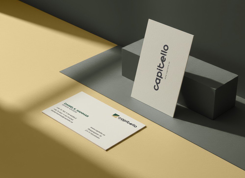 Two Capitello Finans business cards casting sharp shadows on a warm beige surface, used as the project thumbnail for OUF Studio's branding case study.