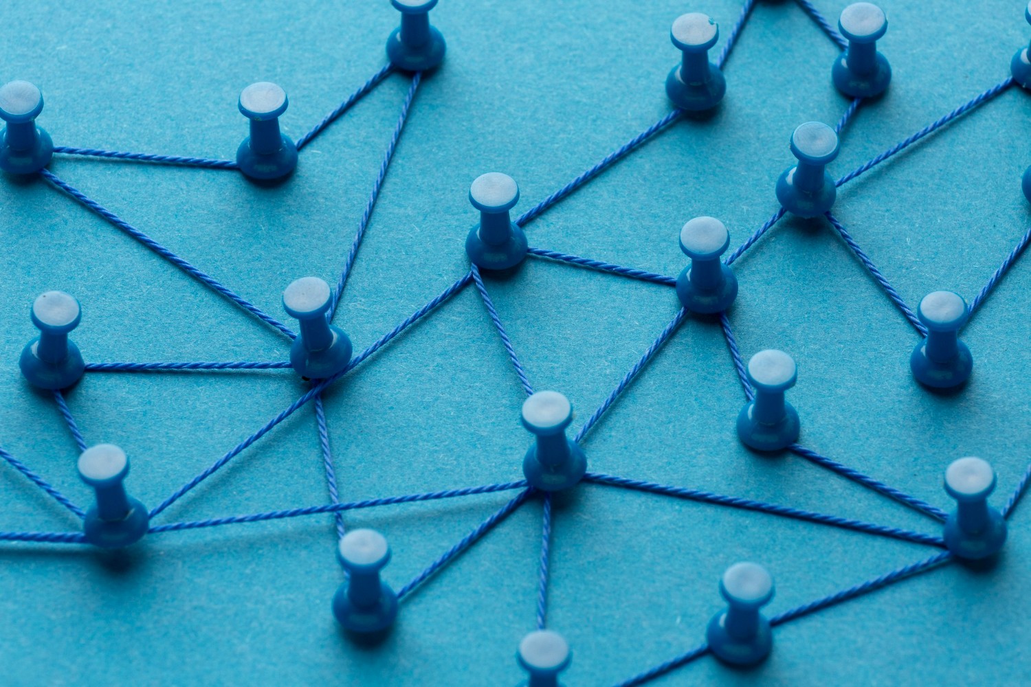 Graphic of network nodes represented by blue push pins on a flat blue background.