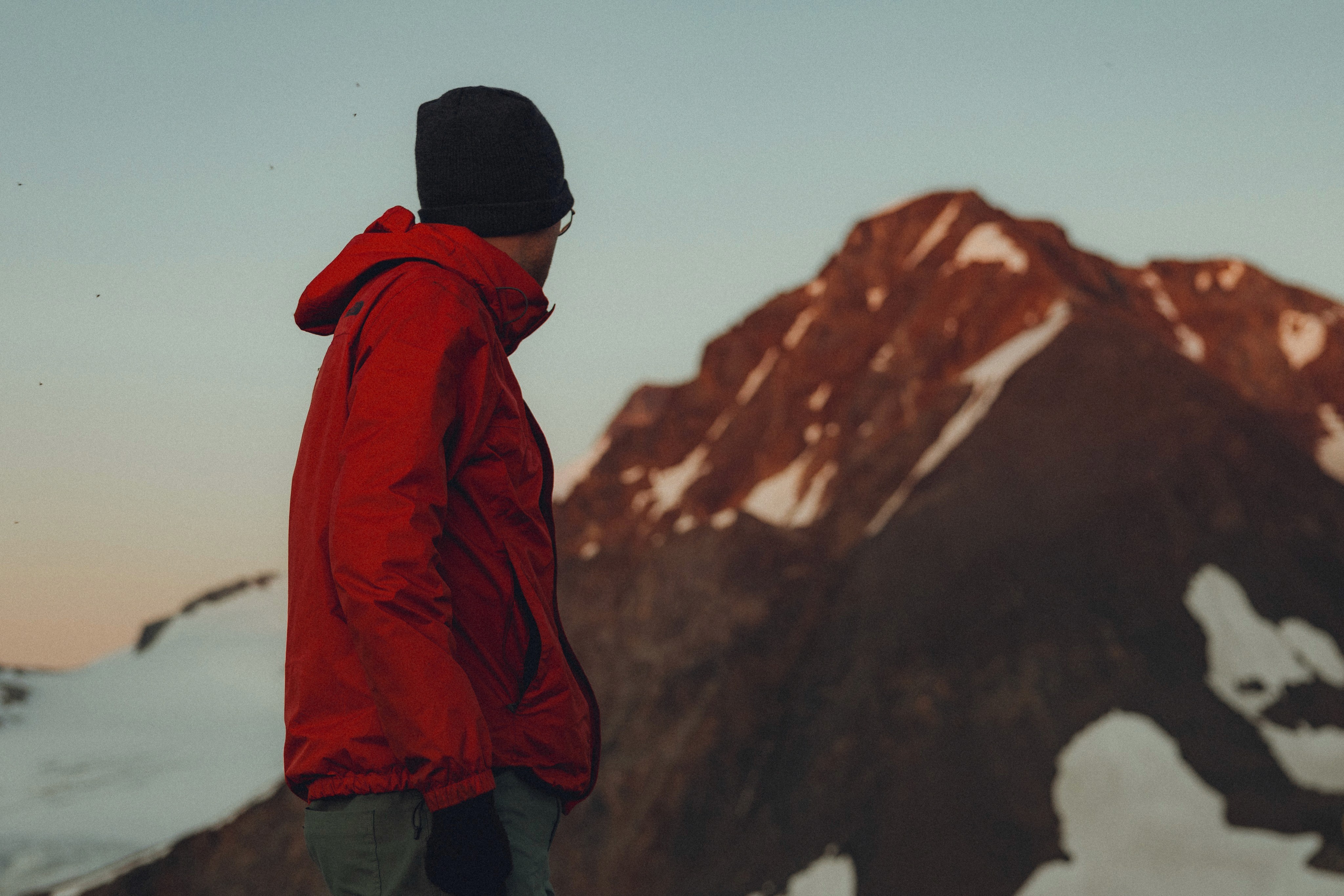 Hiker in a red jacket looking up at a snowy peak in Garibaldi Provincial Park