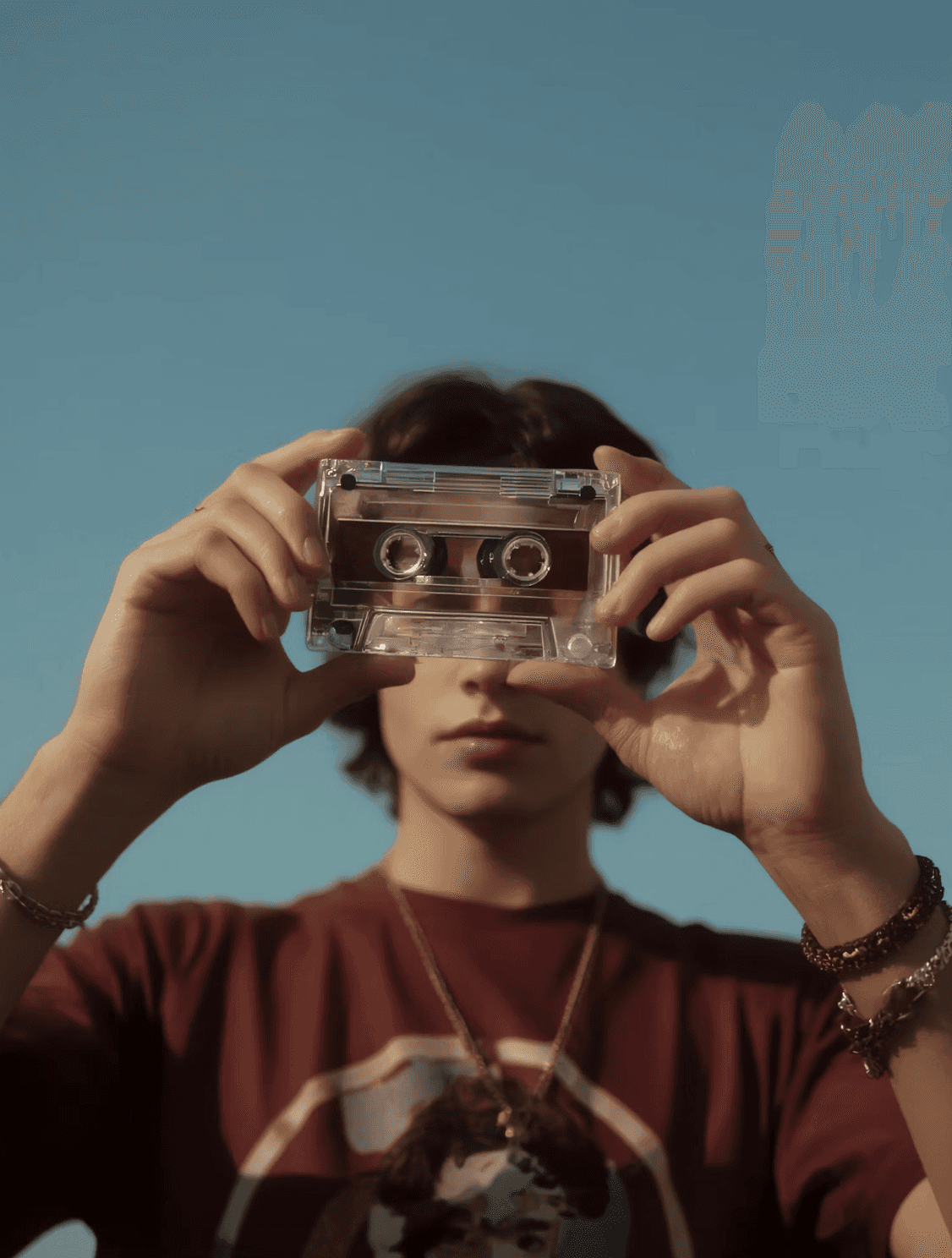 Person holding a transparent cassette tape in front of their face.