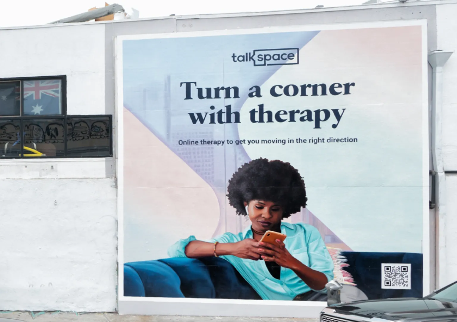 a man walking down a street past a large poster