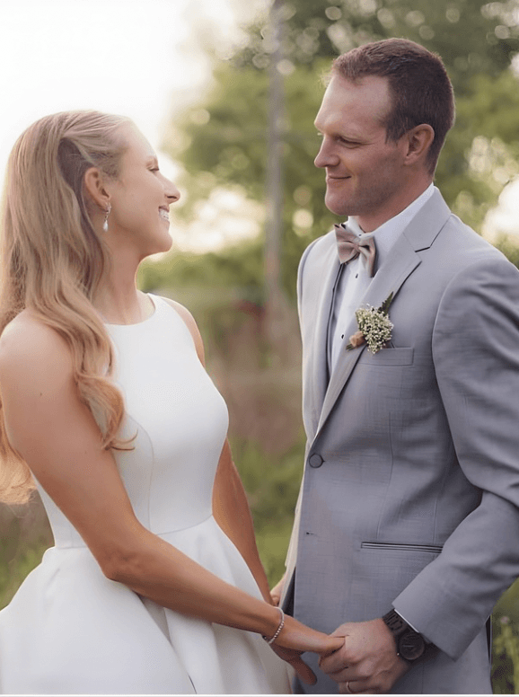 A bride in a lace wedding dress gently holds.