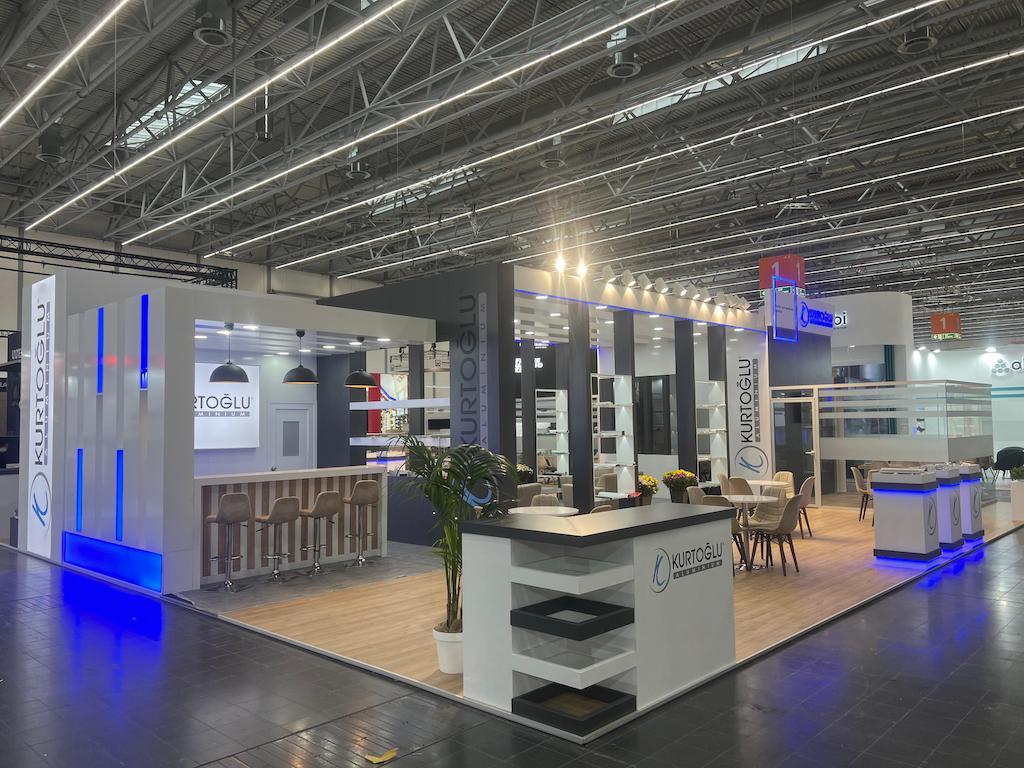 Repeating 'KURTOGLU' logo pattern on a feature wall at the Aluminium 2024 exhibition stand.
