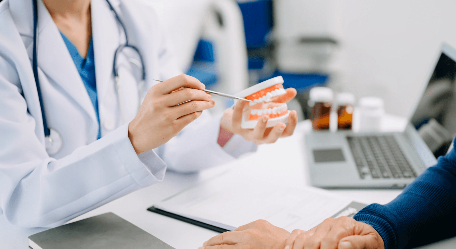 An orthodontist holding a dental model while discussing possible treatment with a patient by Invisalign Center