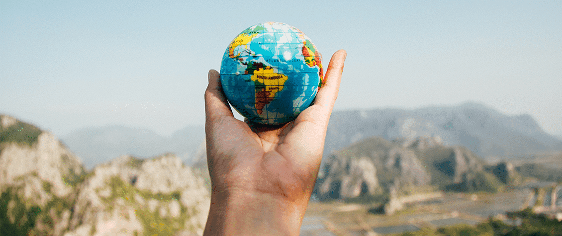 A hand holding a small globe, representing worldwide shipping