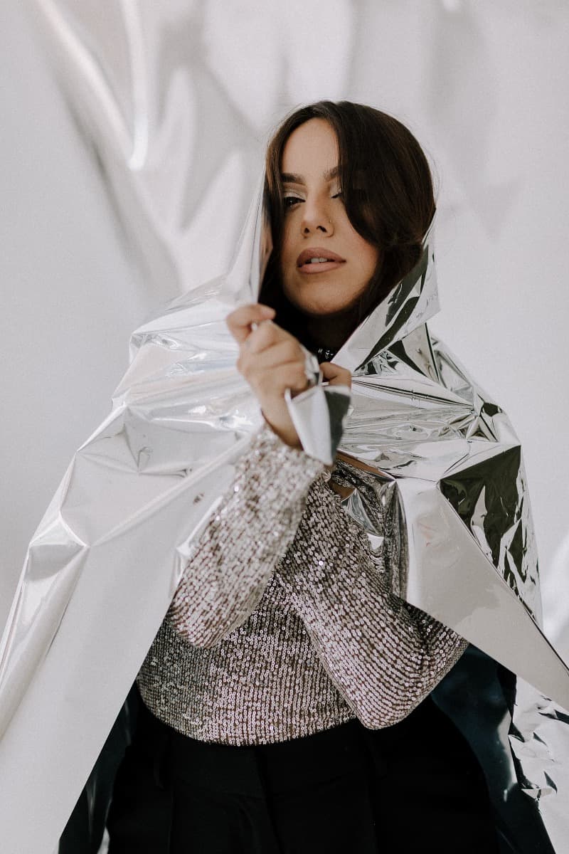 A close-up of a model’s hands on silver reflective mylar, adding texture and shine to the creative shoot at Revelator Studio, a natural light studio in Shreveport.