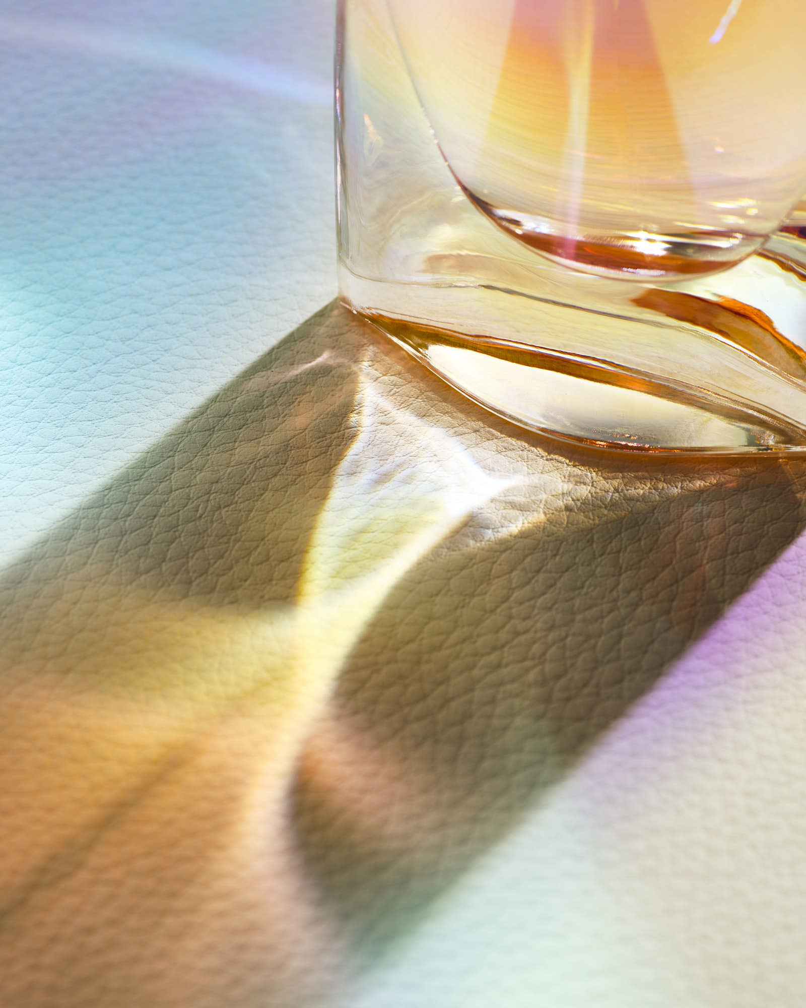 Colorful light reflections from a glass on textured surface.