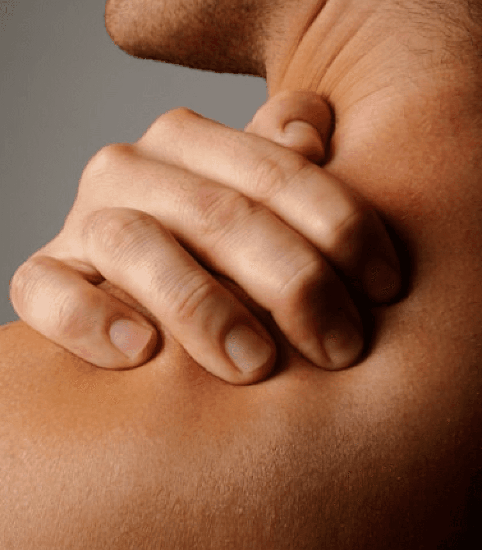 A person is holding their bare shoulder with one hand, indicating potential muscle pain or tension relief, highlighted against a neutral gray background.