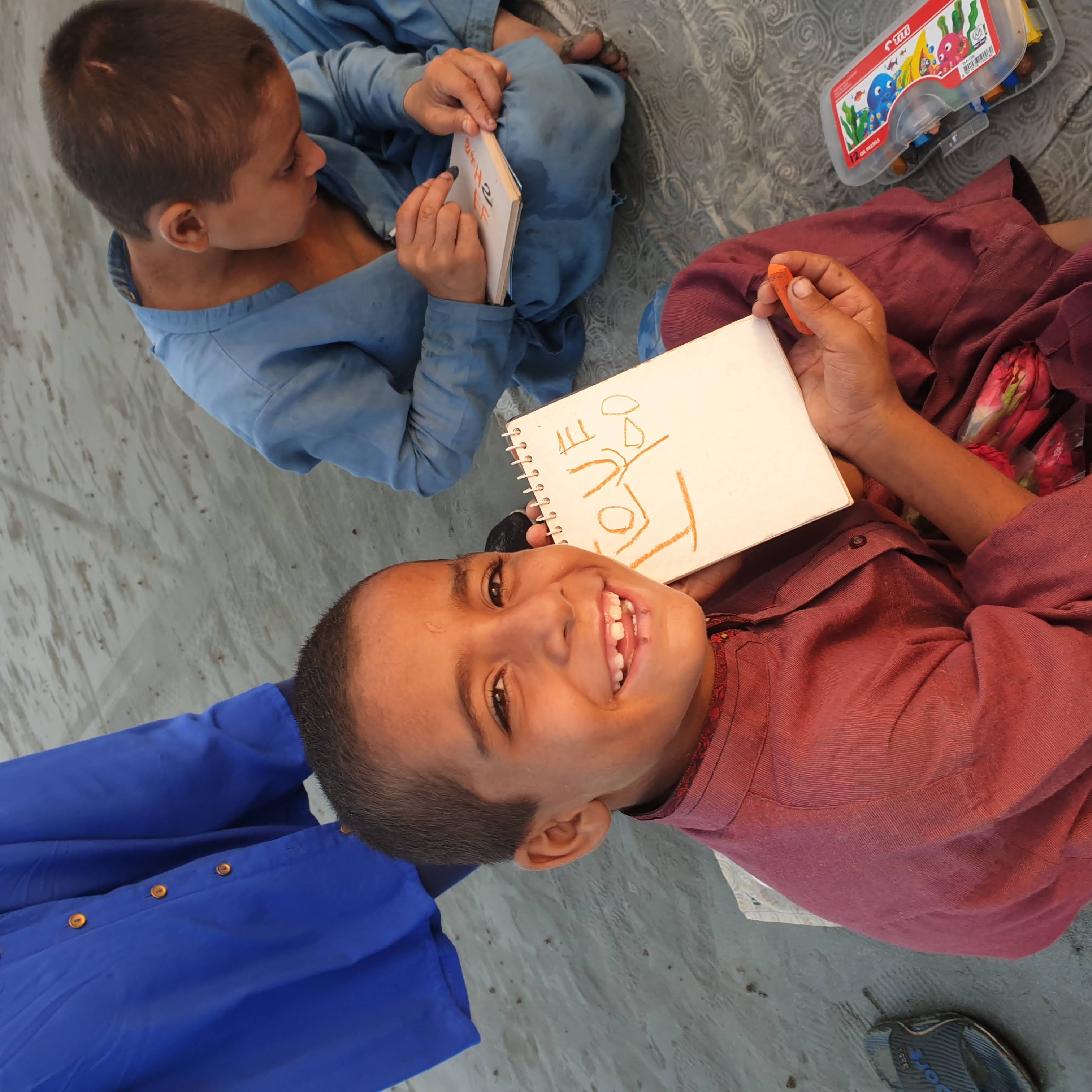 a boy smiling holding a card with i love you written in crayon