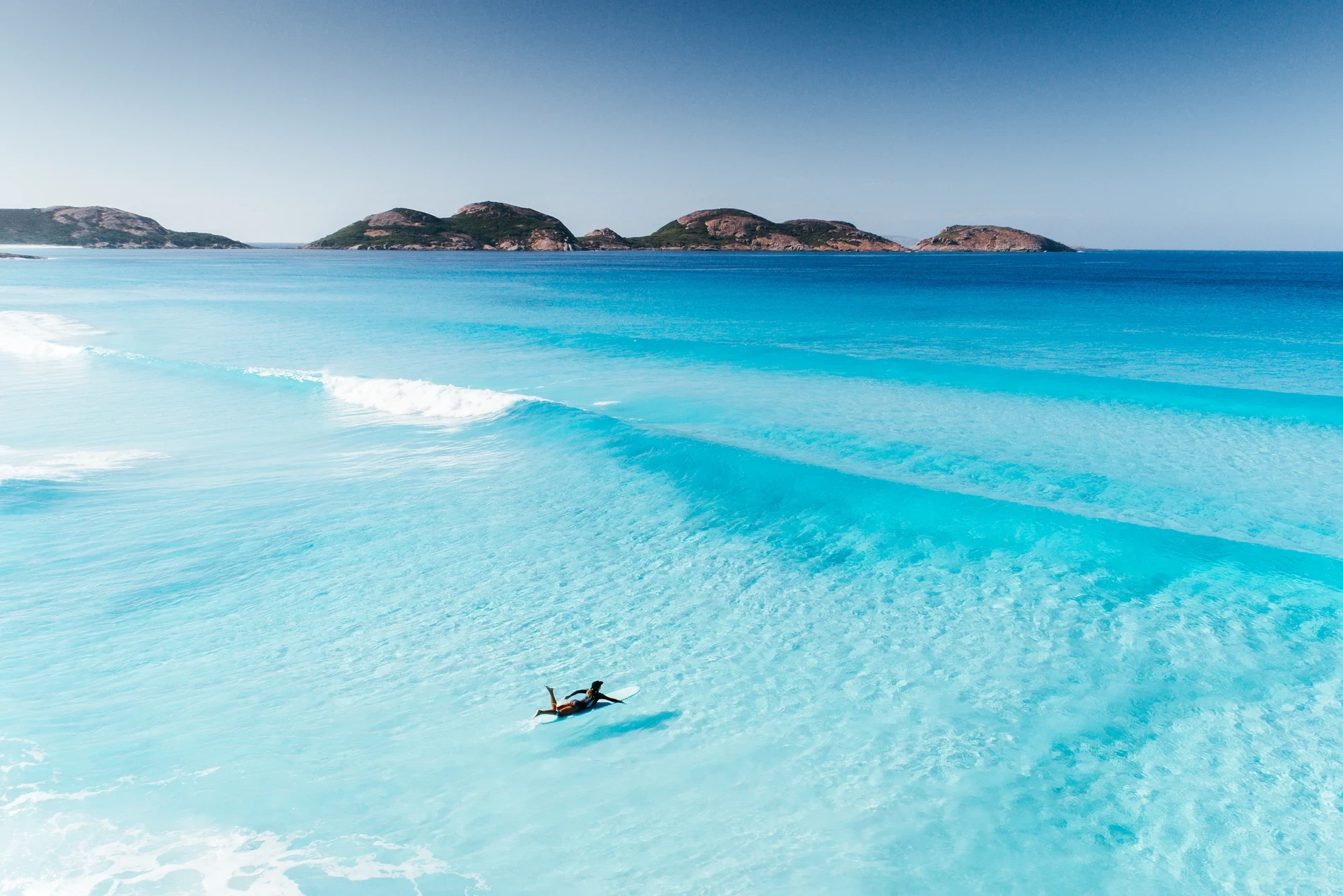 Turquoise shallows and breaking surf below a rocky island chain