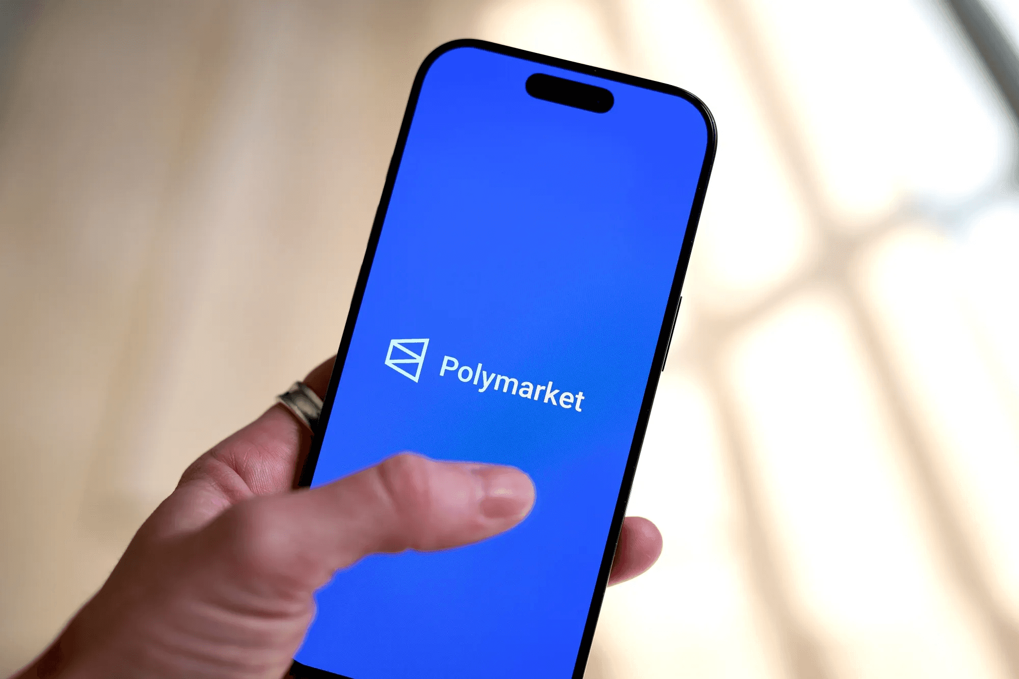 Smartphone displaying Polymarket app - How Old Do You Have to Be to Use Polymarket