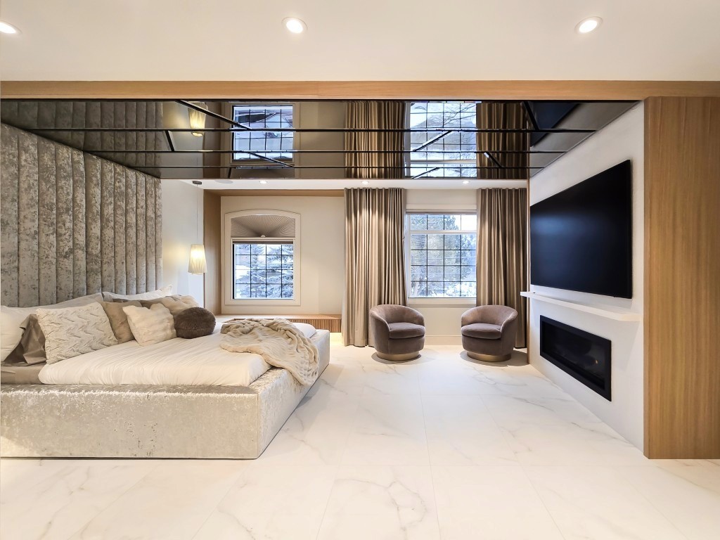 Image of Luxurious primary suite with plush furniture, large TV, and modern window coverings by KHD Homes designers.