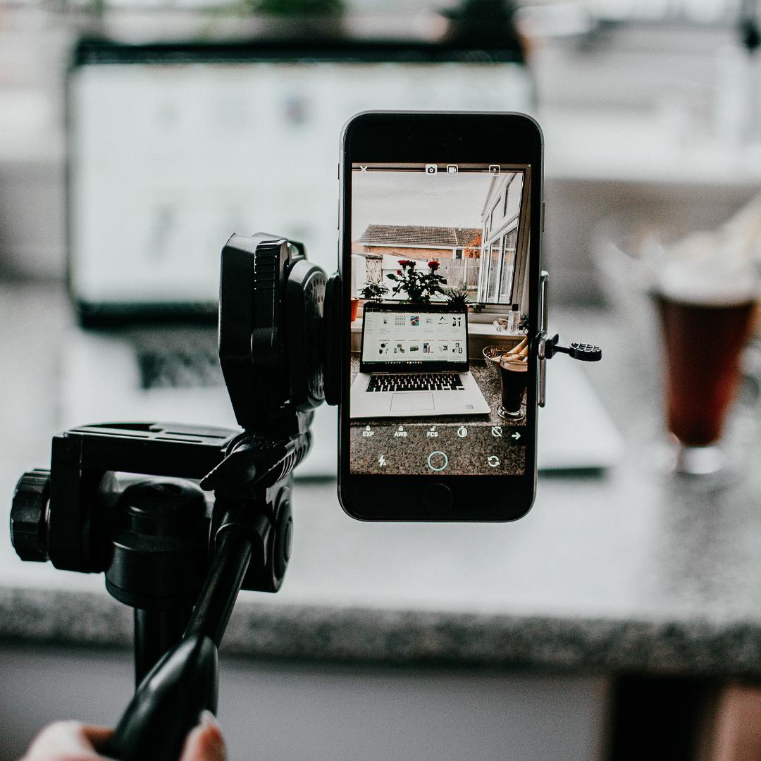 Image of a phone in a tripod taking a video of a laptop